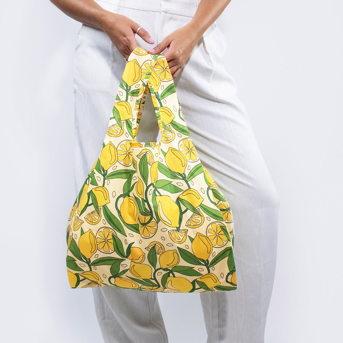 Image showing Regusable bag by Kind bag in vibrant lemons print, shown slung over a woman's arm.