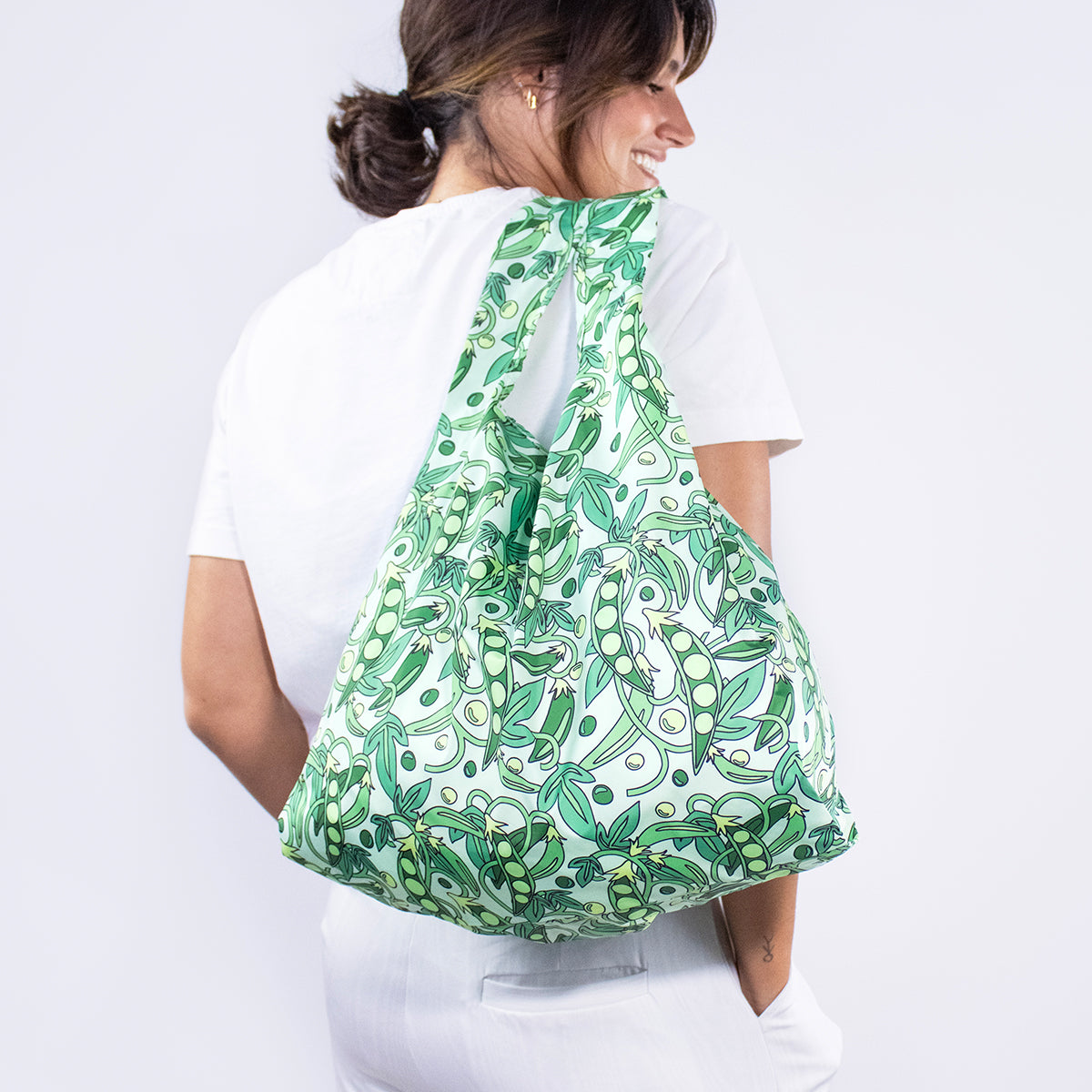 Image showing Regusable bag by Kind bag in green peas print, shown slung over a woman's shoulder.