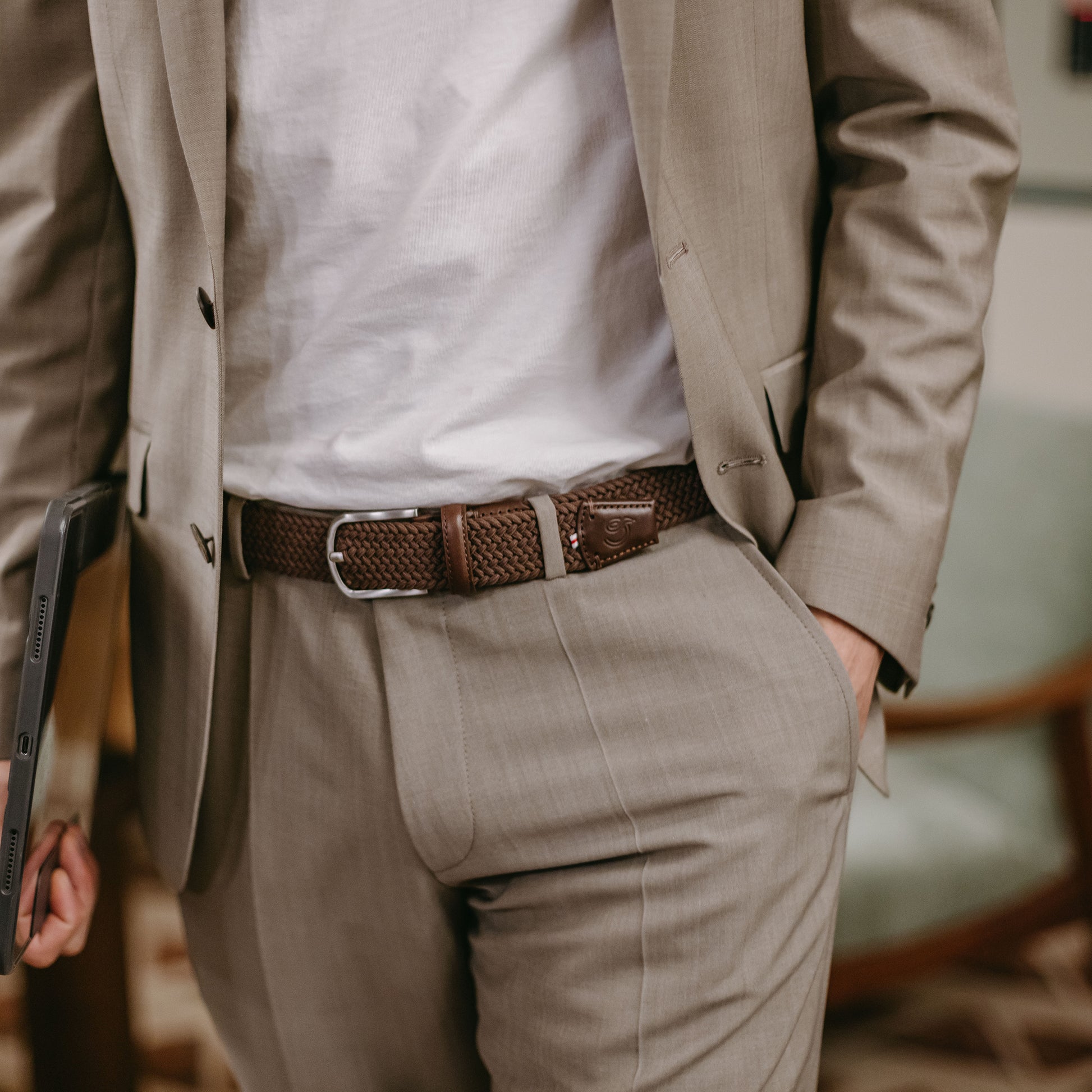 Man wearing La Boucle mono edinburgh woven belt around beige pants and white t-shirt and beige jacket