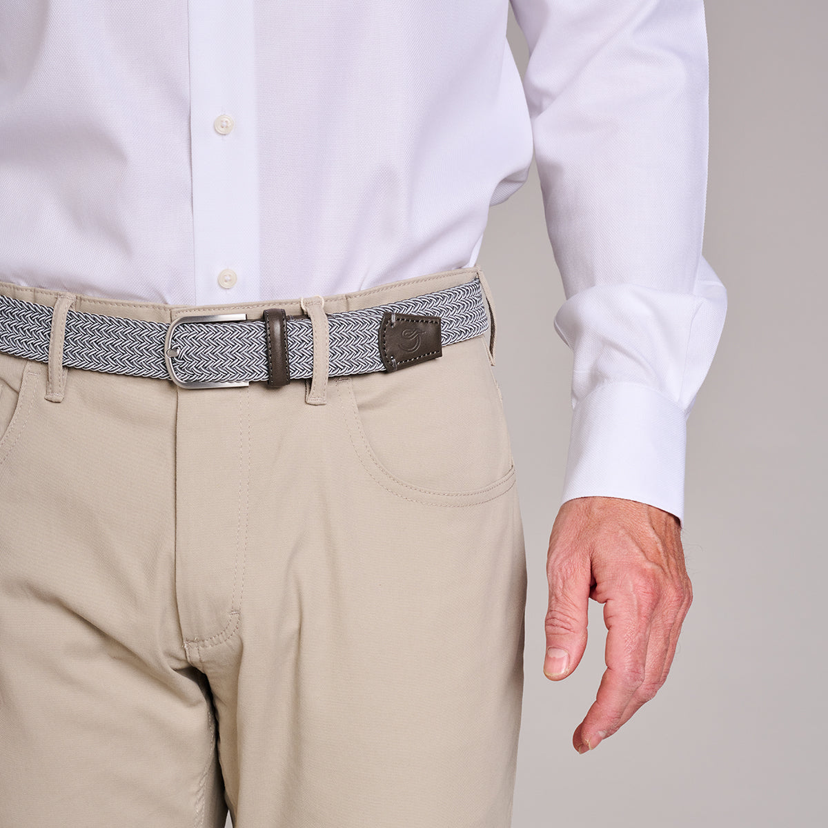 Man wearing La Boucle mono forte dei marmi woven belt around beige pants and white shirt on grey background
