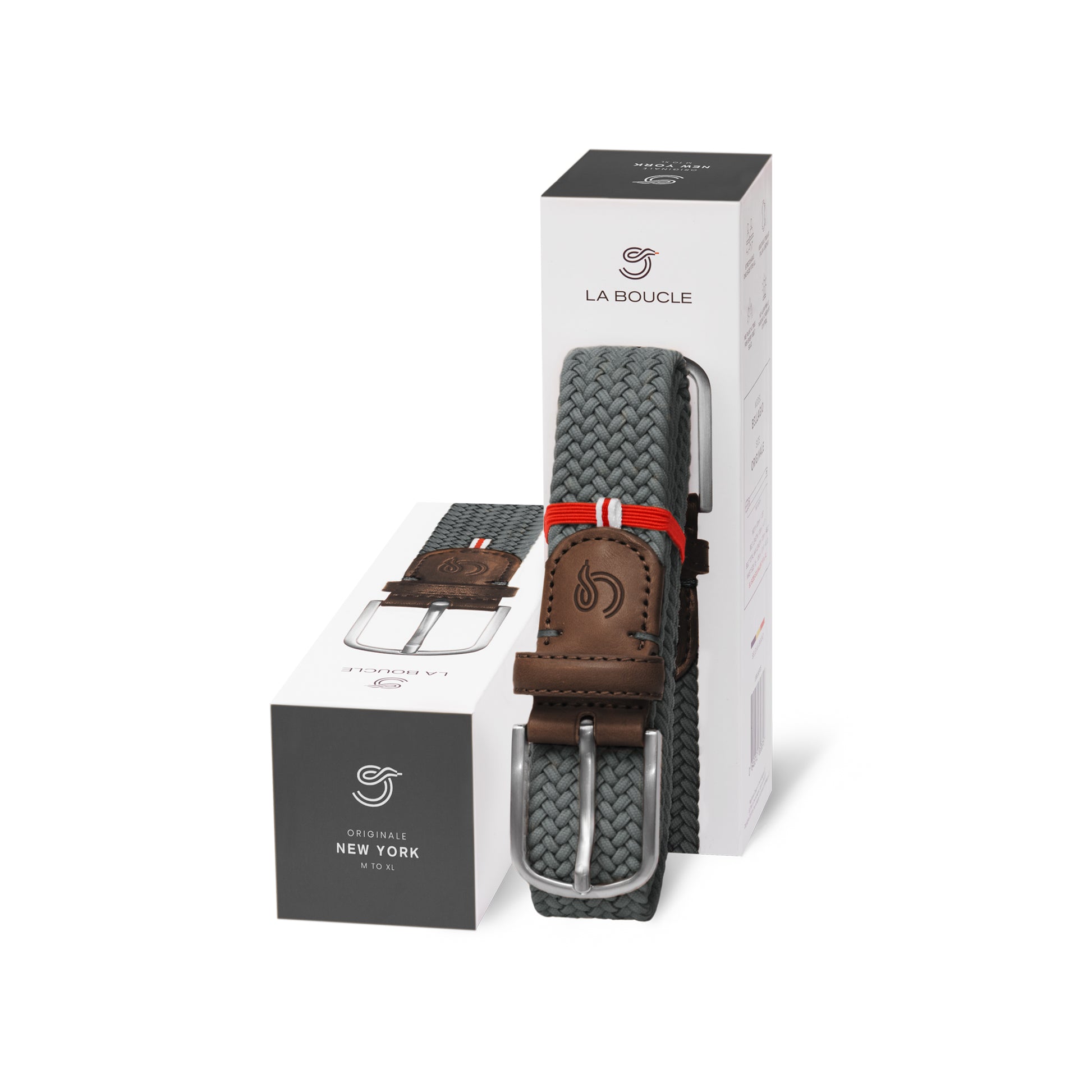 La Boucle mono New York woven belt folded and leaning on a box next to a box on white background