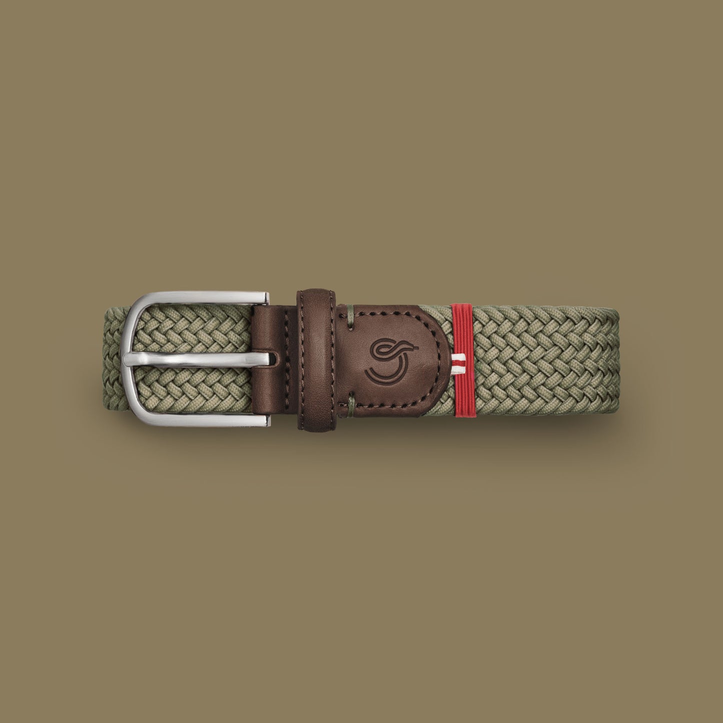 La Boucle mono Verbier woven belt folded and leaning on a box next to a box on white background
