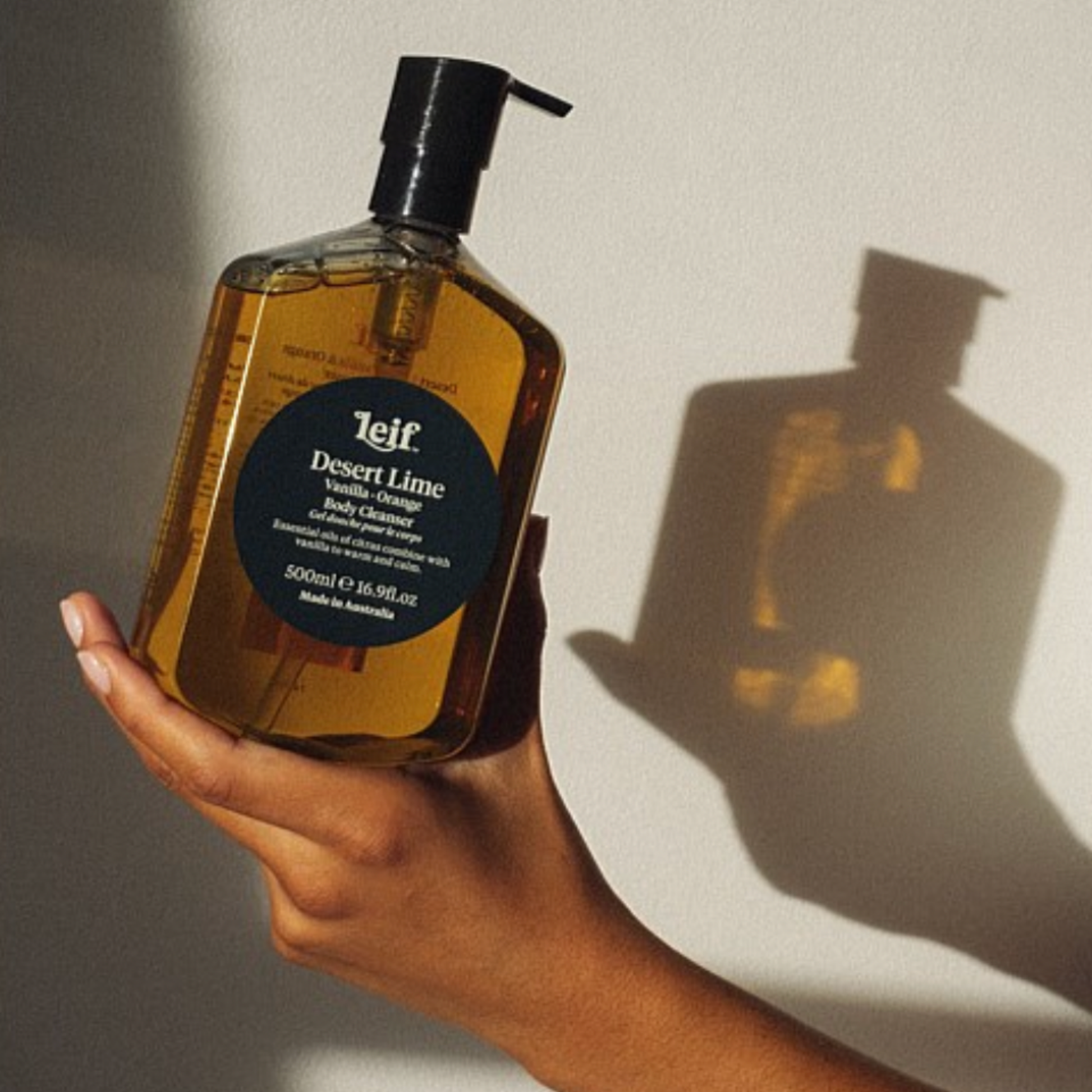 Hand holding Leif body cleanser Desert Lime 500ml in soft lighting