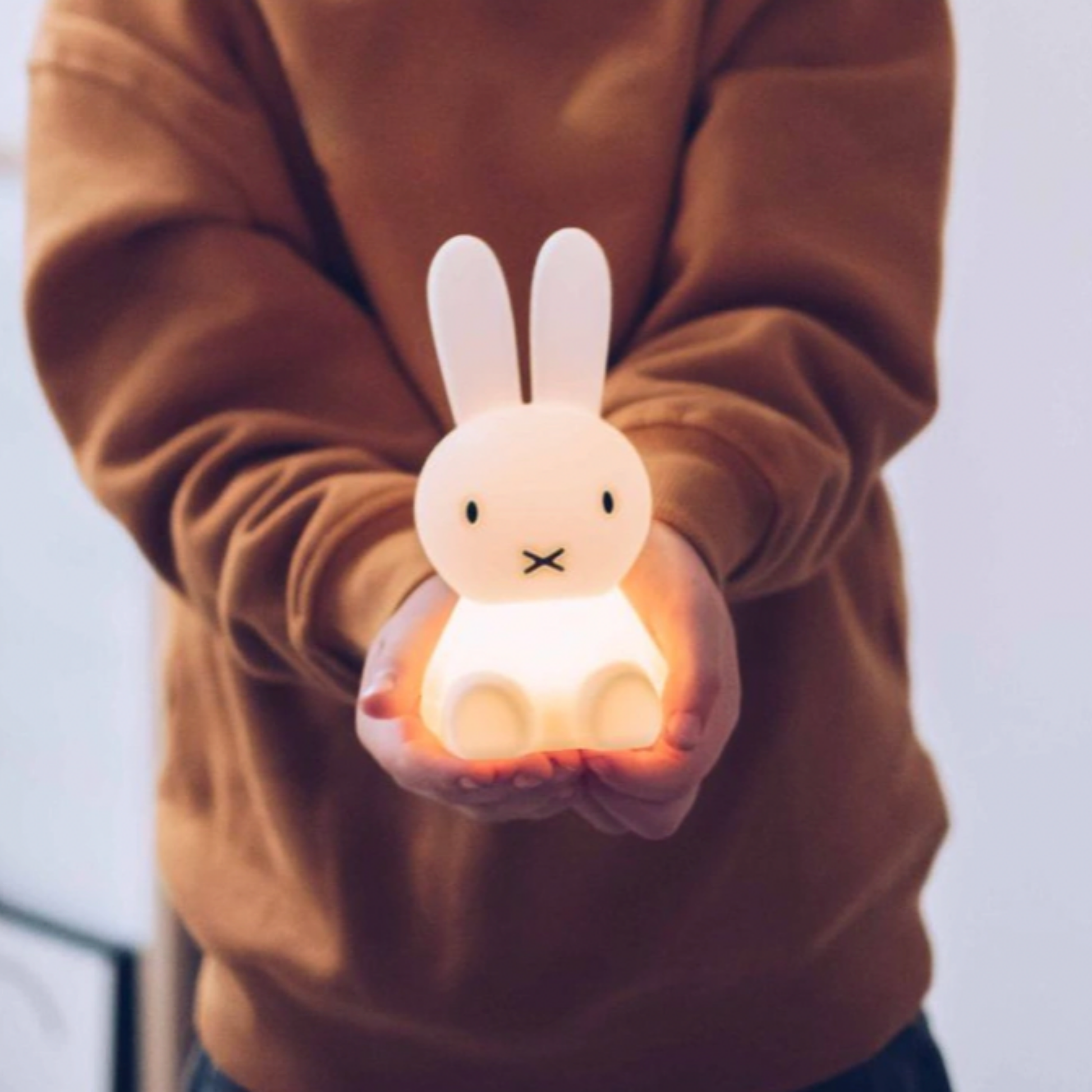 Small child holding Mr Maria decorative Miffy night light in palms facing camera 