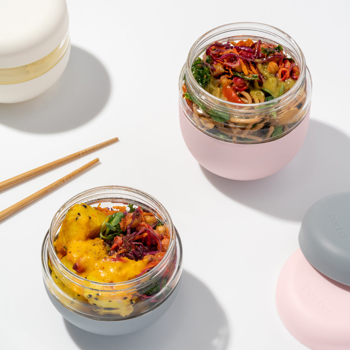 WP seal tight glass bowl 710ml blush filled with noodle salad next to other seal tight bowls and chopsticks on white table