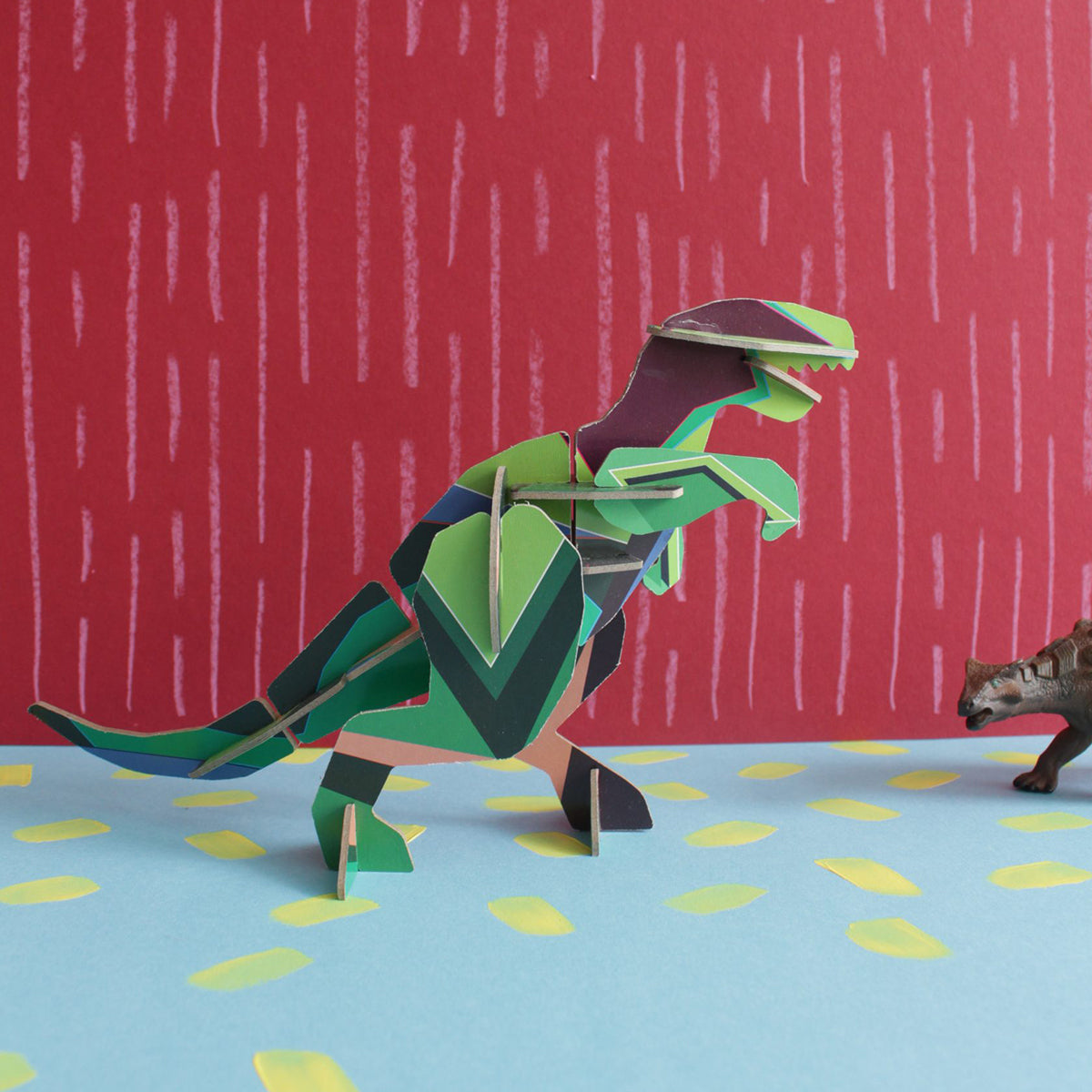 Studio Roof B6 creative play card t-rex standing on blue floor with yellow dots and red background with white lines