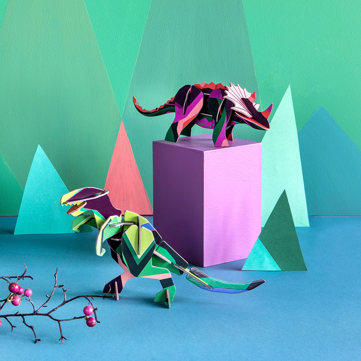 Studio Roof B6 creative play card t-rex standing on a blue floor next to a triceratops on top of a pink box