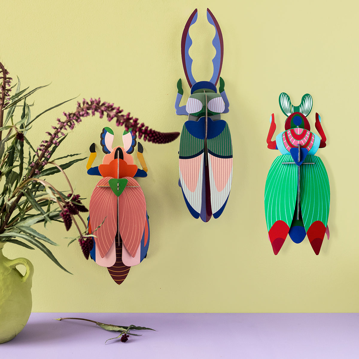 Studio Roof A4 lady beetle wall art hanging on a yellow background next to two other bugs