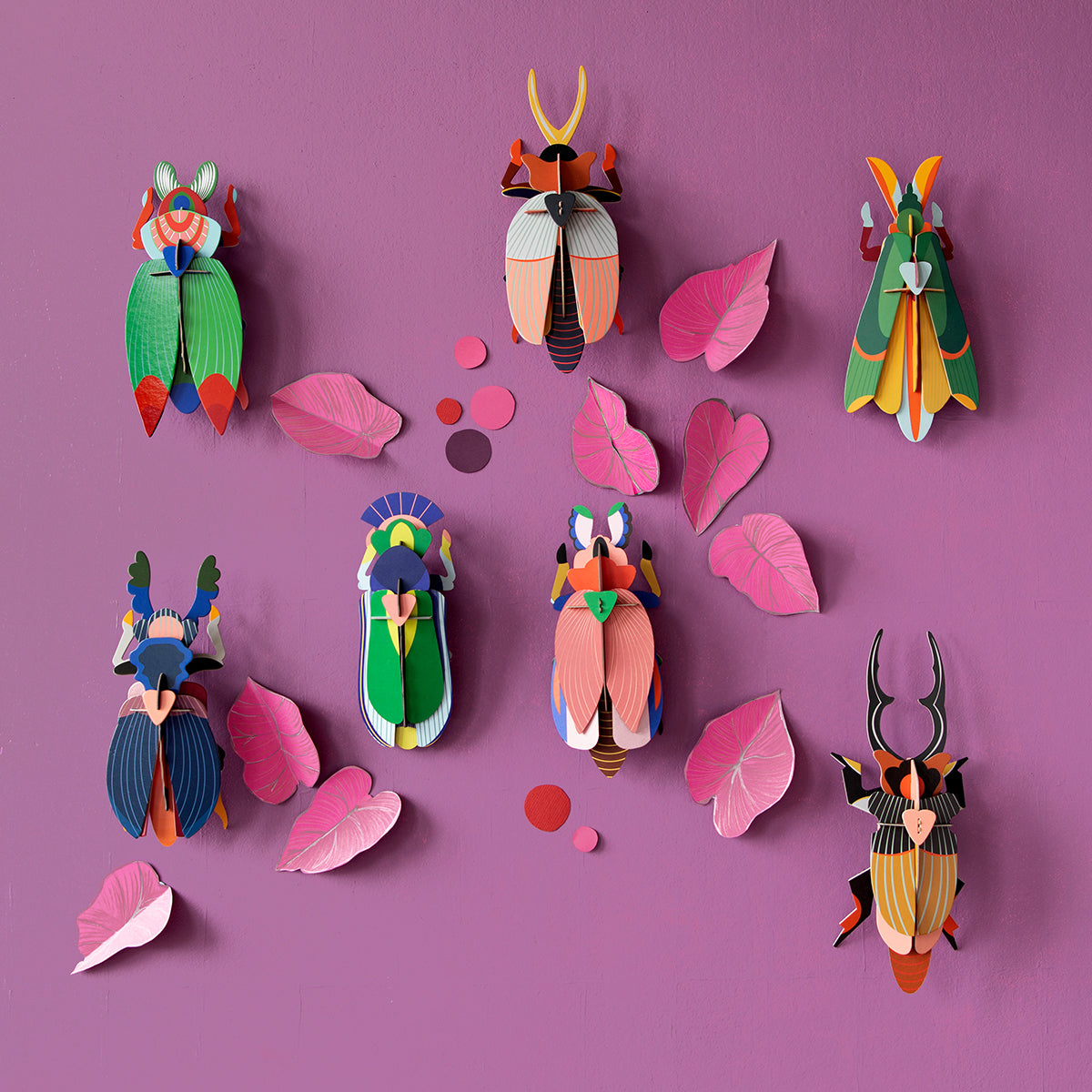 Studio Roof A4 lady beetle wall art hanging on a dark purple background next to five other bugs and pink paper leaves