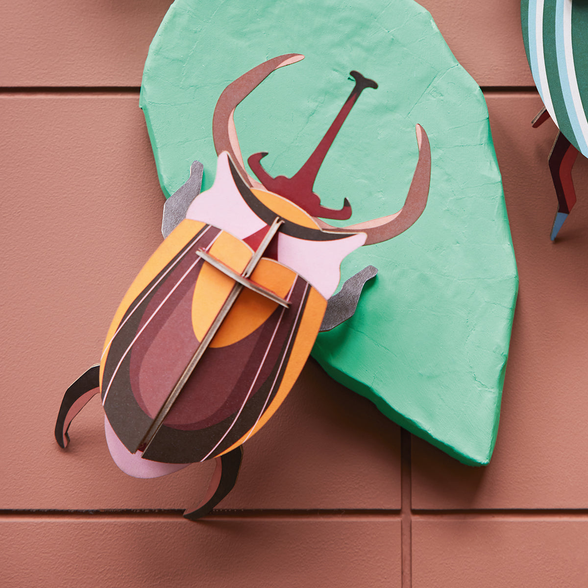 Studio Roof B7 elephant beetle wall art climbing on green leavf on brown background 