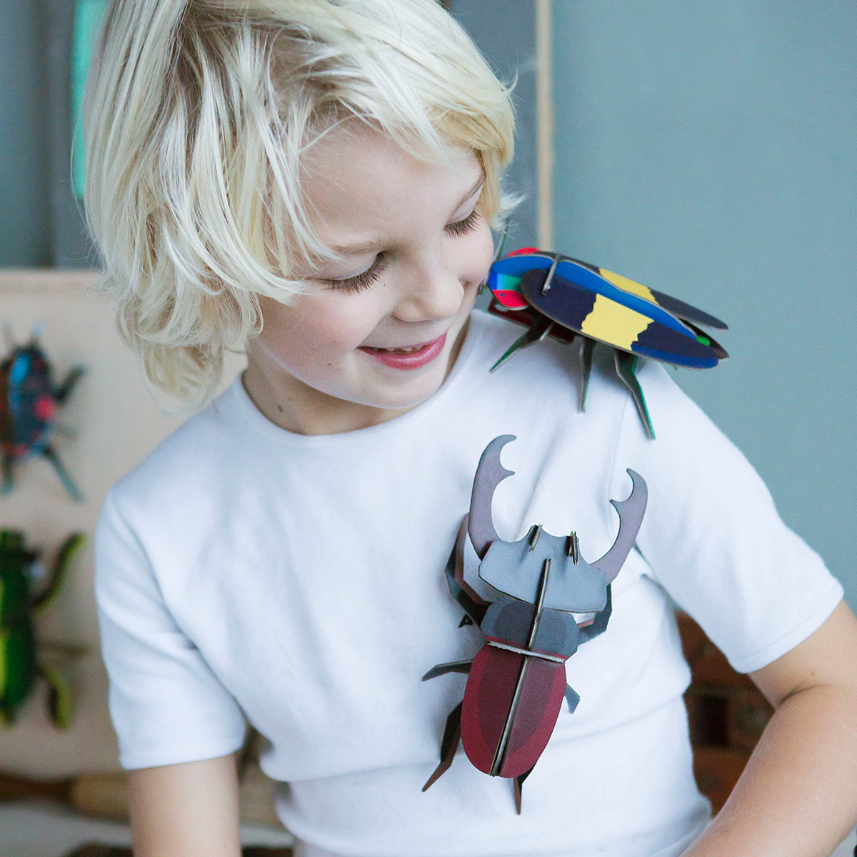 Studio Roof B7 stag beetle wall art climbing on small boy wearing white tshirt with blonde hair