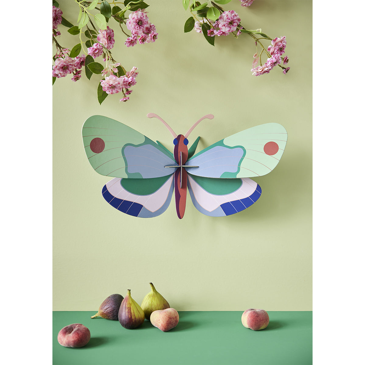 Studio Roof A4 mint forest butterfly wall art and other beetles mounted on mint wall above dark green surface with delicate flowers