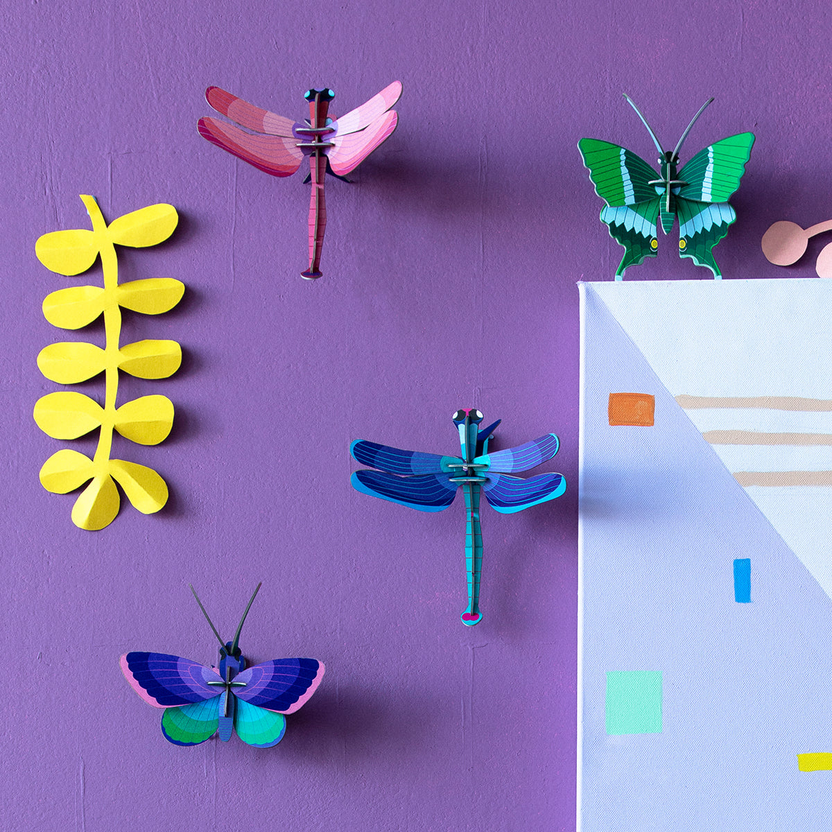 Studio Roof B7 blue copper butterfly wall art on dark purple wall next to other butterflies and yellow paper plant 