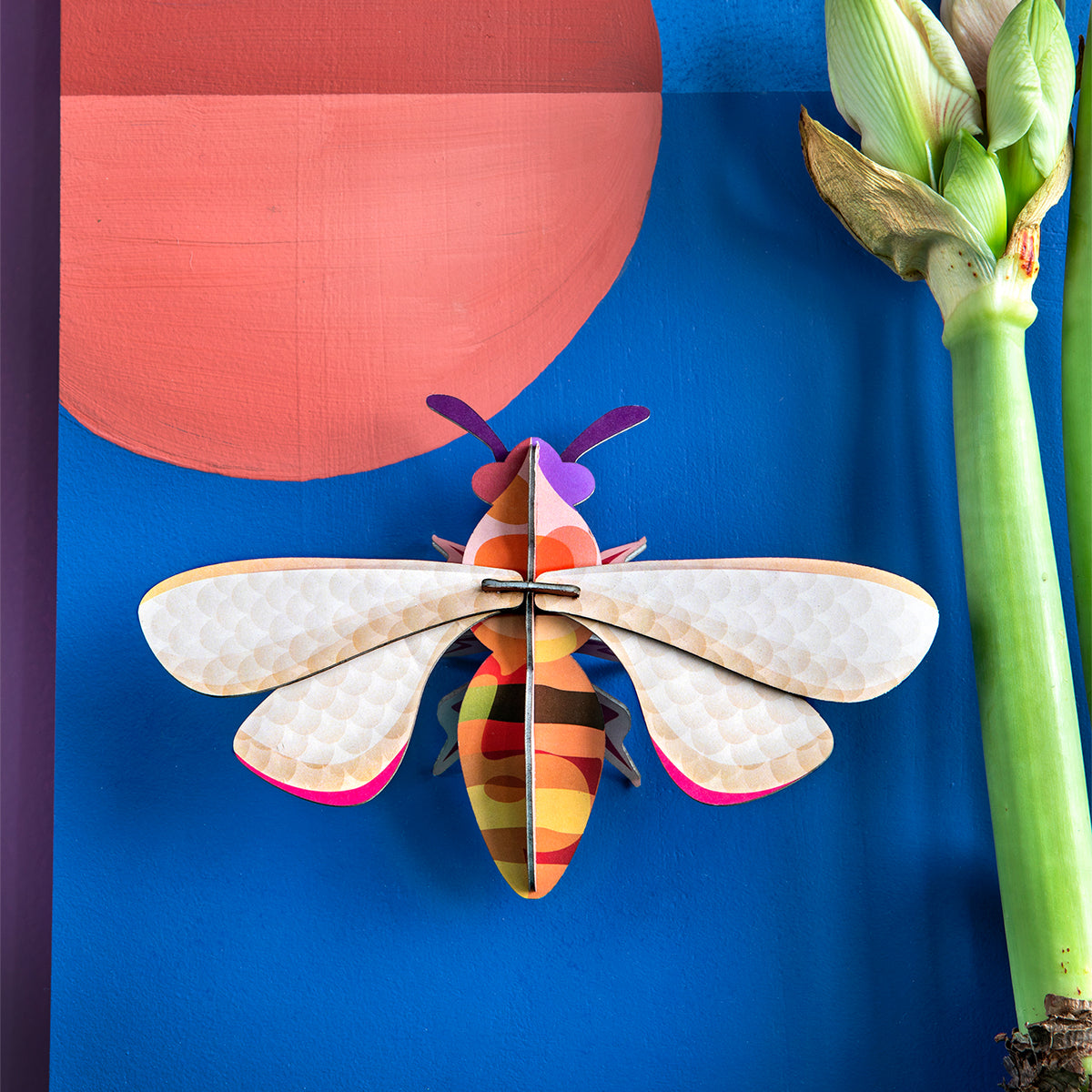 Studio Roof B7 honey bee wall art on blue surface with peach dot and paper asparagus 