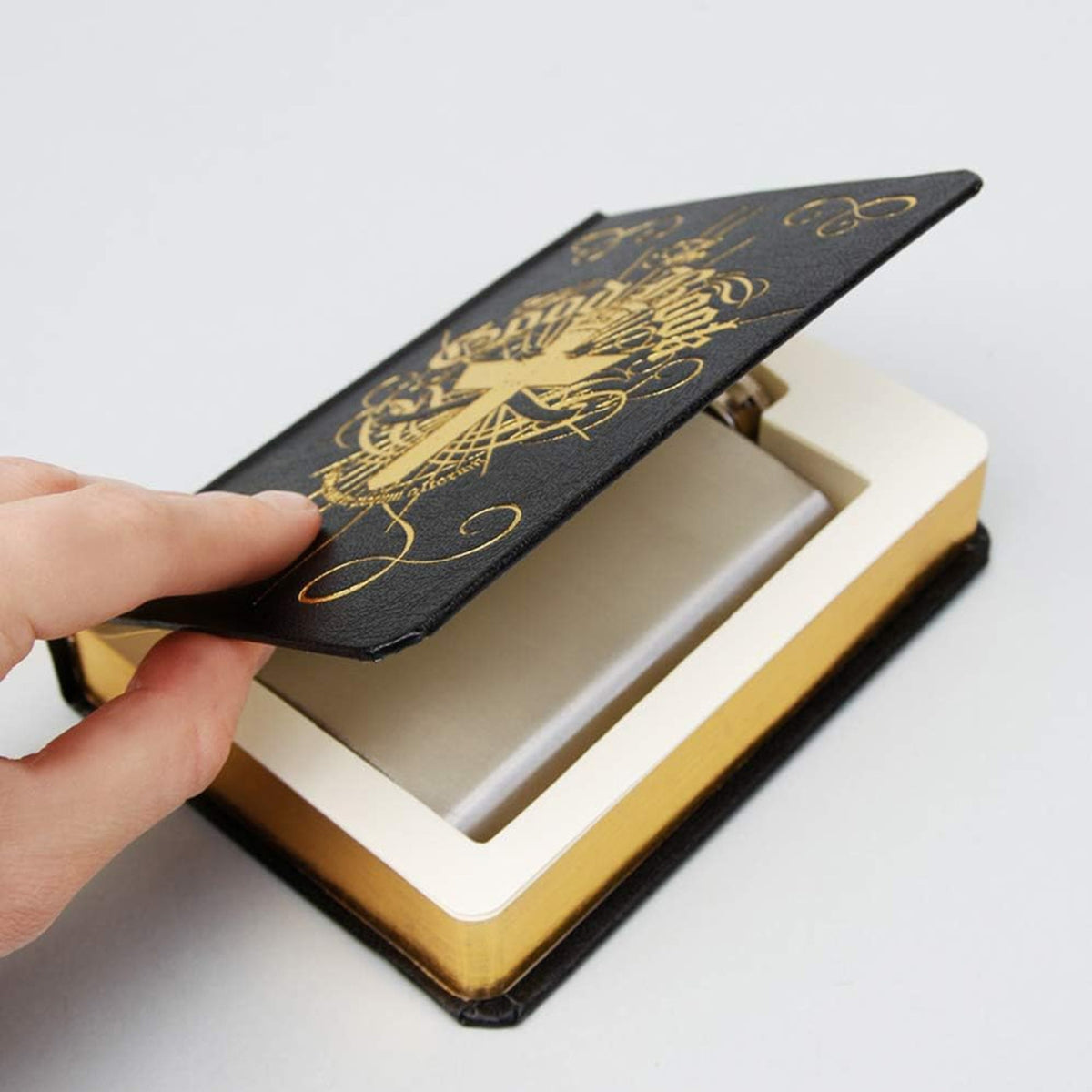 Semi-open book and a flask laid on a surface, Suck UK hidden flask in a fancy hardback book, featuring a 4oz stainless steel hip flask concealed inside. A novelty secret stash gift, perfect for drink lovers, barware collectors, or anyone who wants a discreet, fun way to carry their favourite drink.