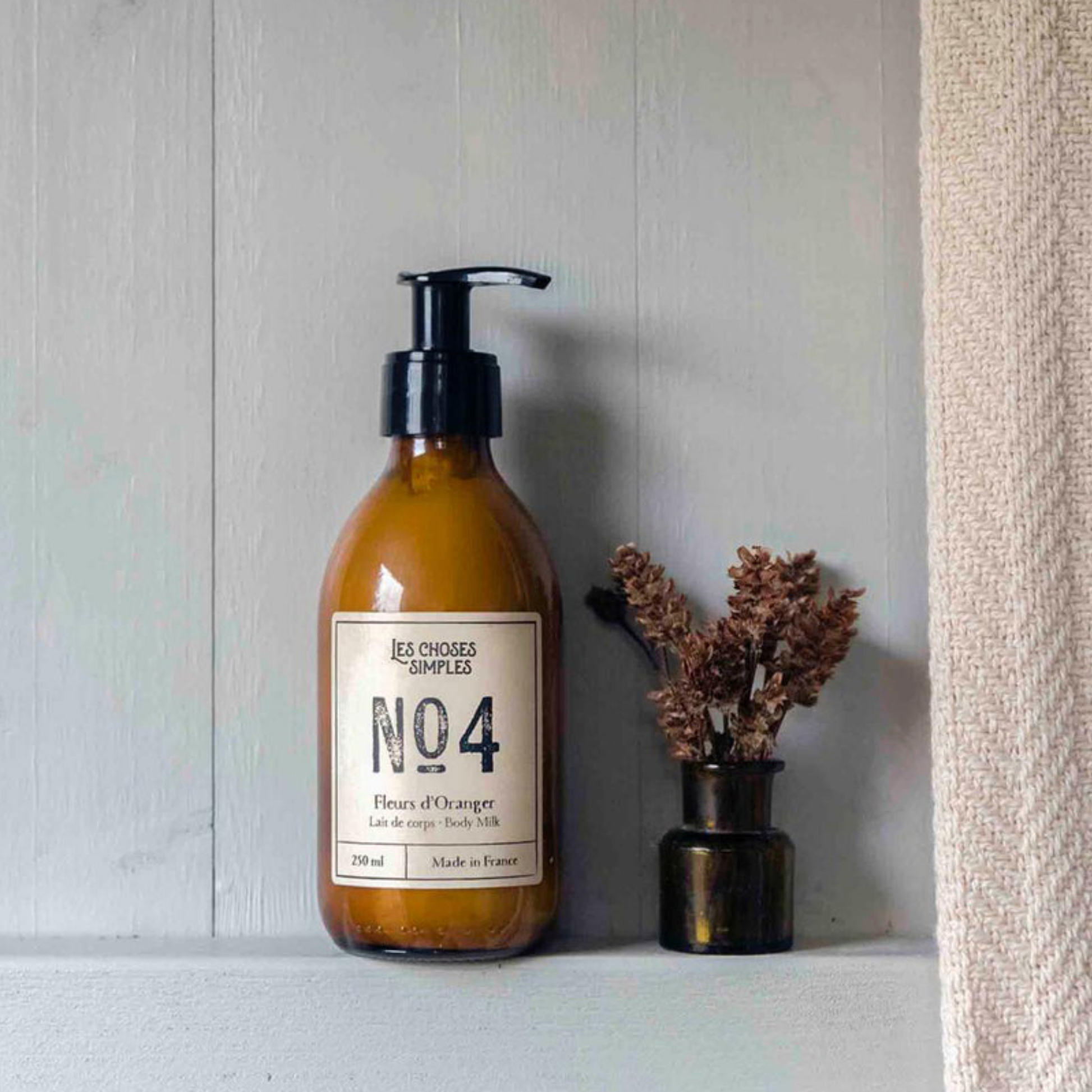 Les Choses Simple Shea Butter Body Milk 250ml Fleur des Oranger on display on bathroom ledge next to towel and flowers 