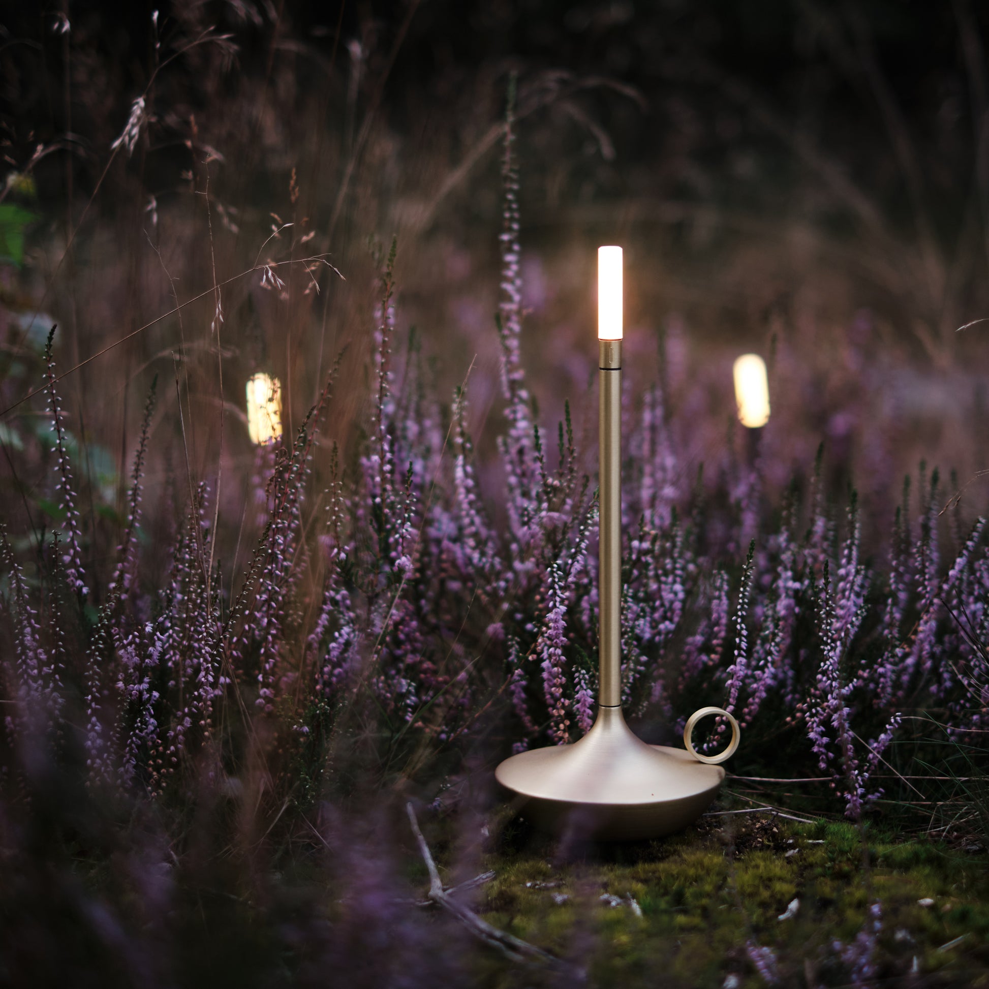 Retro LED lamp in style of candlestick with brass finish displayed in garden