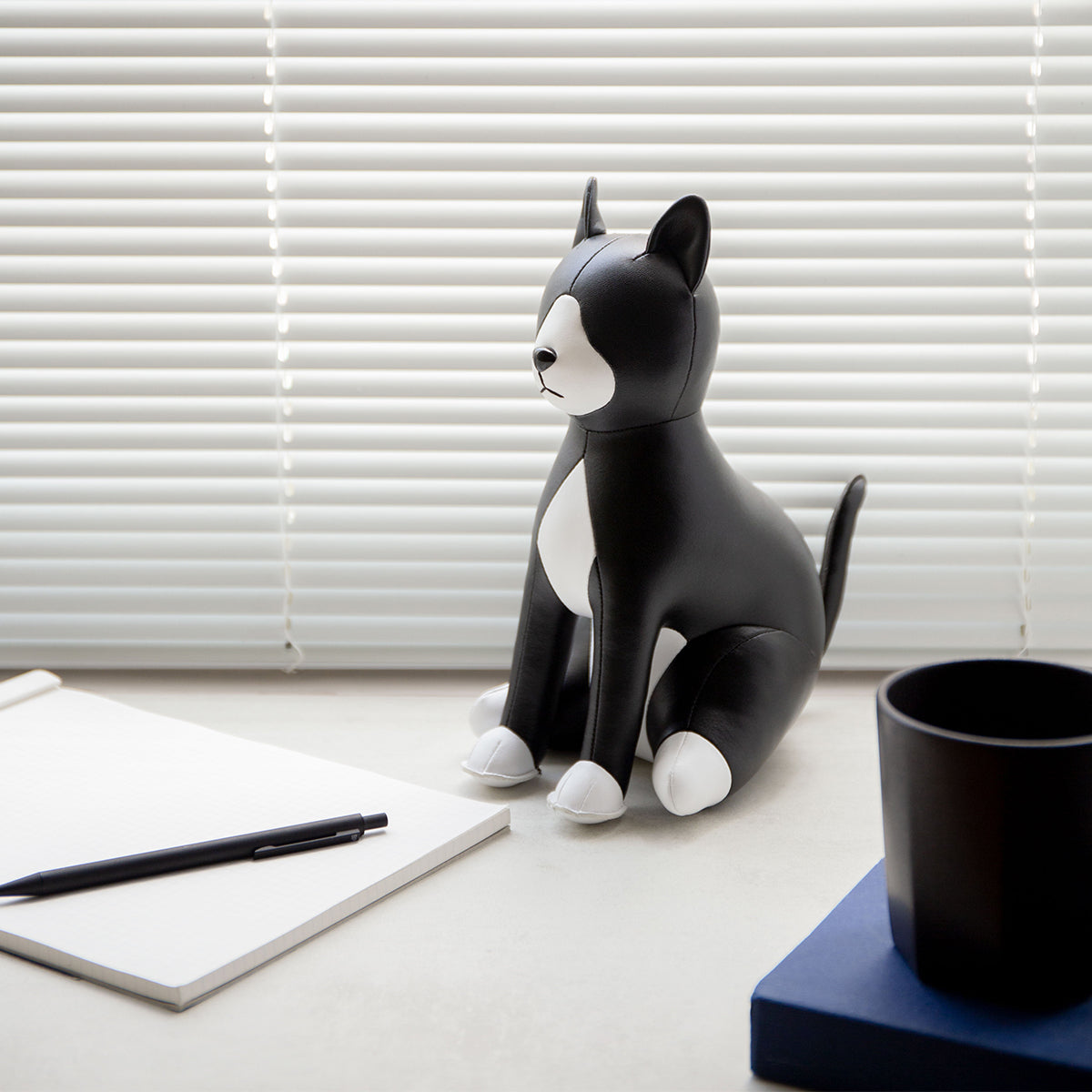 Doorstop sized Cat Tuxedo Black by Zuny shown sitting on a desk.
