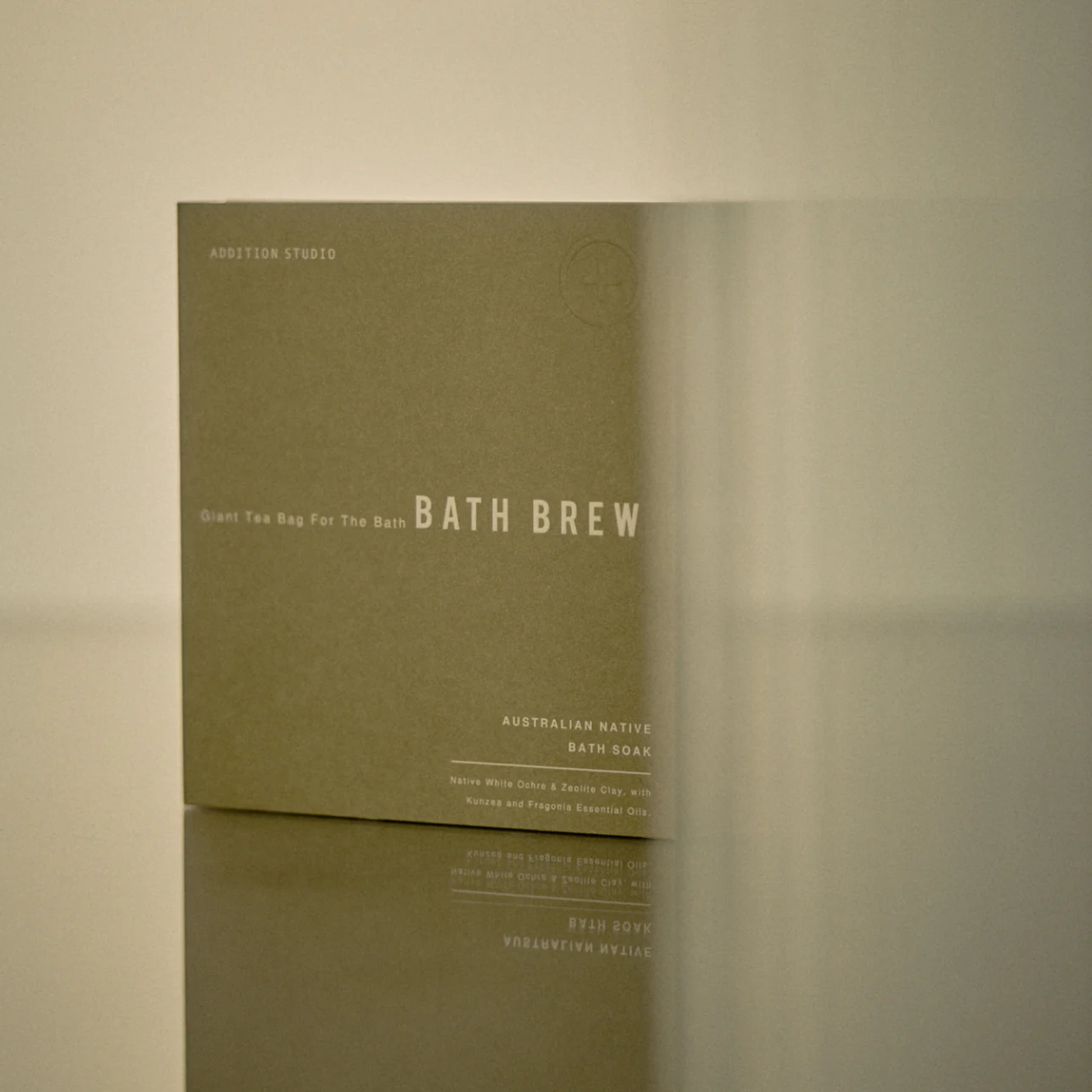 Standing on a surface the packaging of the Addition Studio Bath Brew - Australian Native: Made with Australian white ochre to protect skin, zeolite clay, and kunzea.