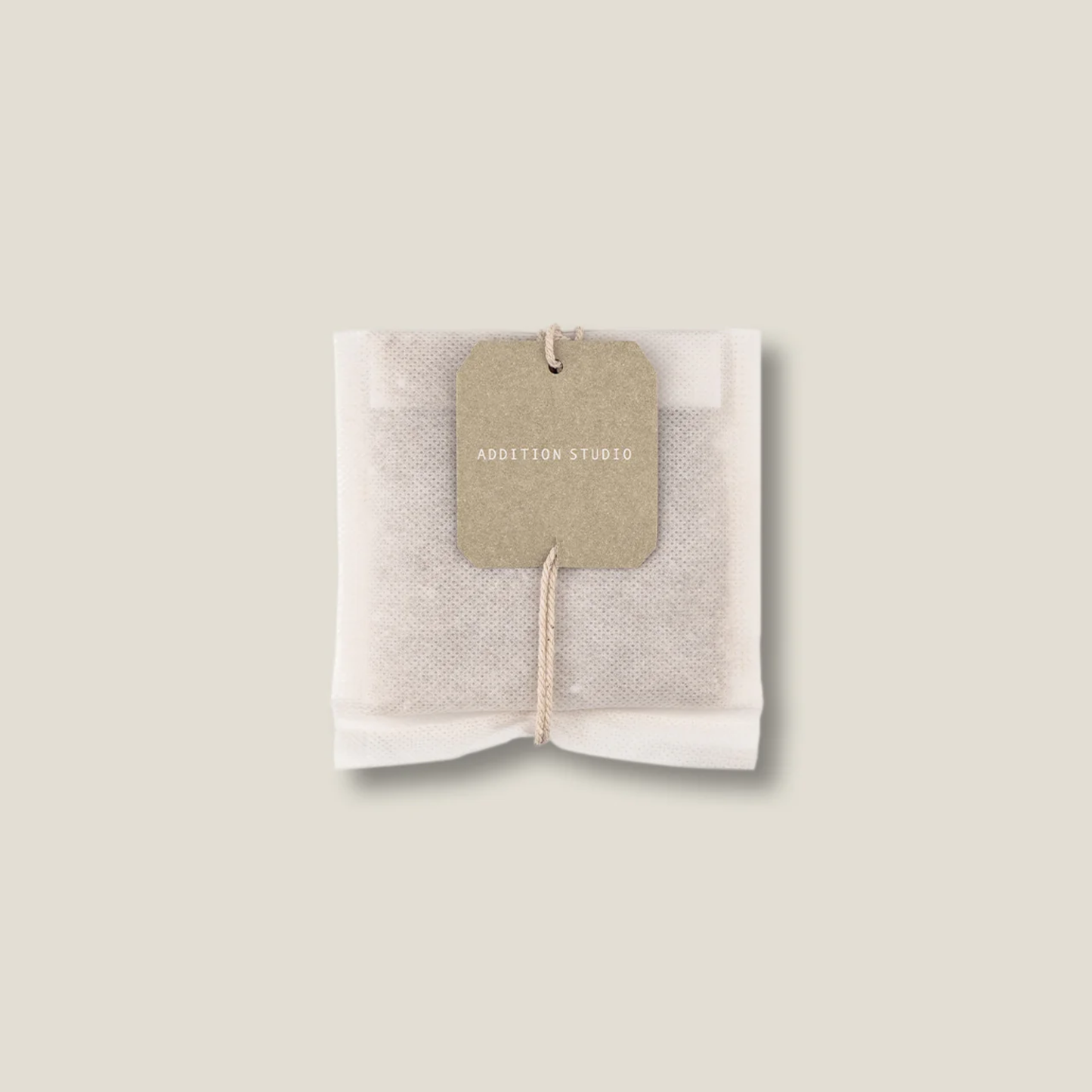 Tea bath bag upclose view of the Addition Studio Bath Brew - Green Tea (75g): Made with matcha green tea, organic seaweed, tea tree, and calendula to help soothe irritated skin, reduce inflammation, and support skin restoration.