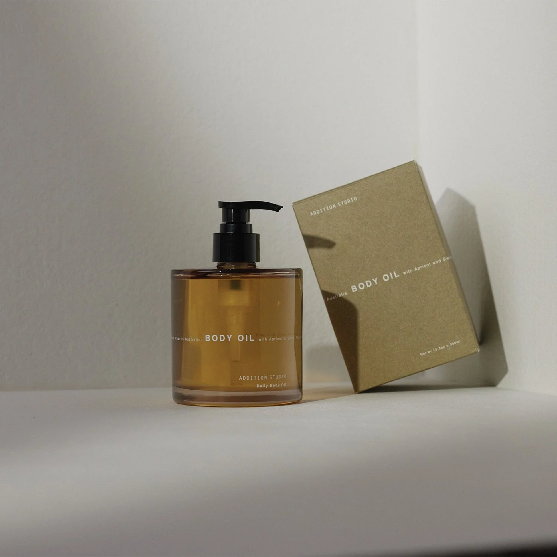 Addition studios body oil with packaging box on angled in white backgroumd 