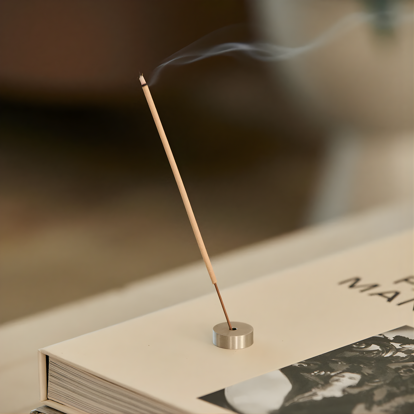 An incense stick in use from Addition Studio Incense Refill Blue Gum & Lemon Myrtle, a 15 stick incense in a green box with fresh blend of rosalina, may chang, atlas cedarwood, and white cypress.