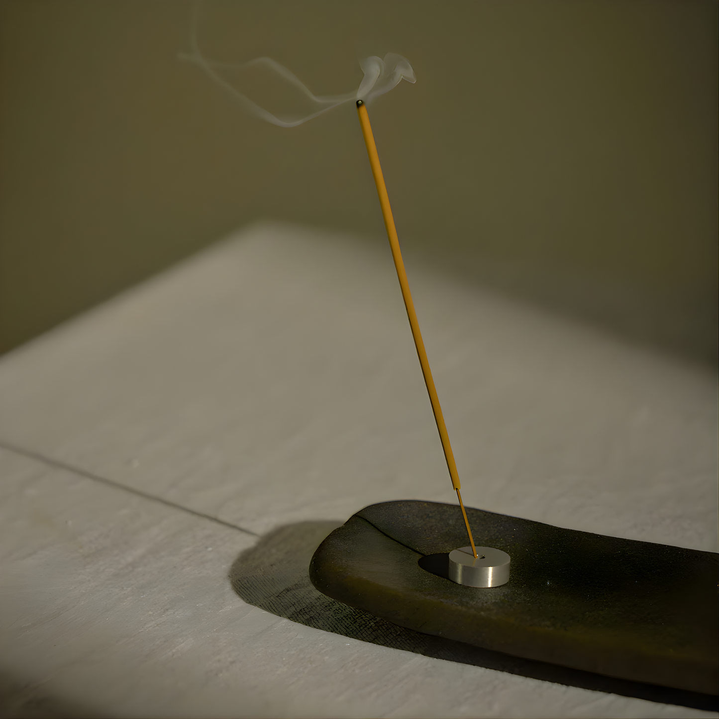 An incense stick in use standing in little holder, from Addition Studio Incense Refill Mandarin, Lime & Basil: a 15 incense stick in a box, with a blend of mandarin, sandalwood, lime, basil, and aniseed essential oils.