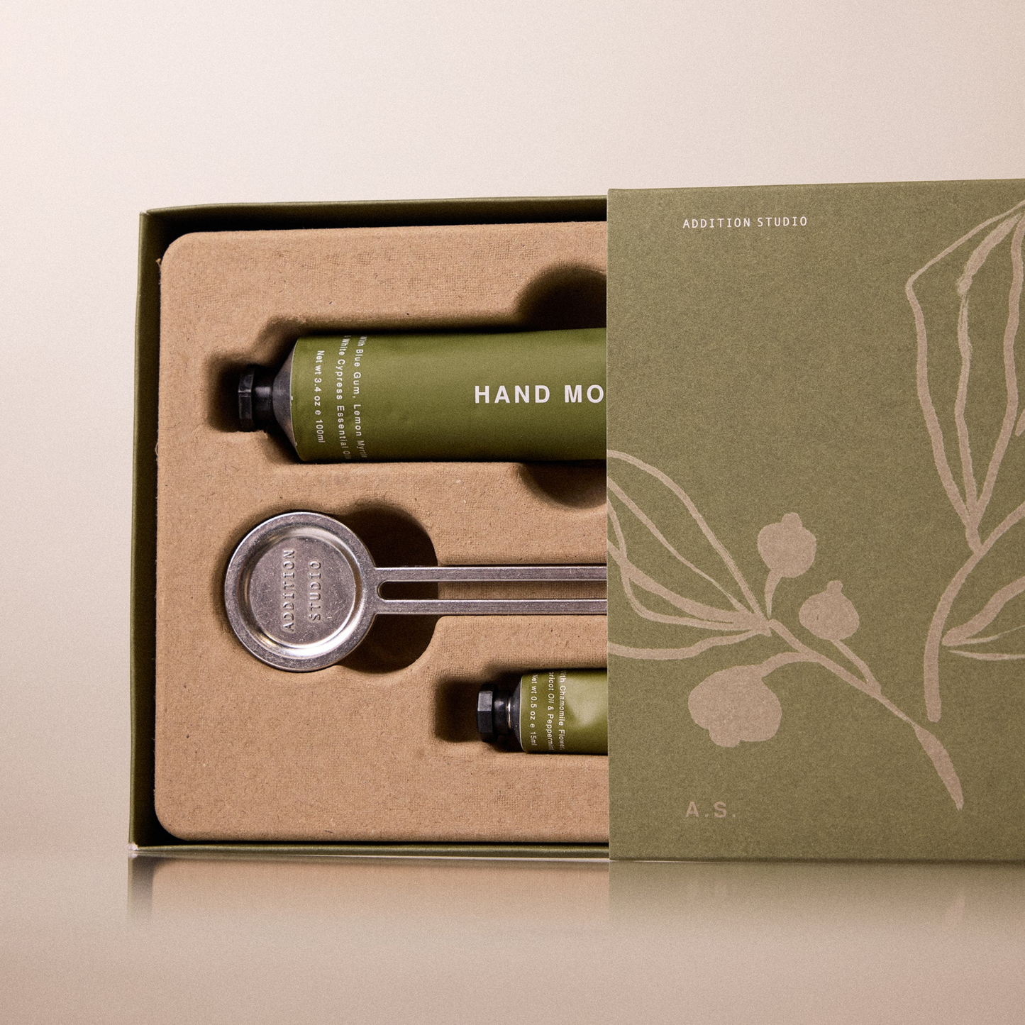 Open box for the Addition Studio Squeeze the Day Set that Includes Hand Moisturiser (100ml) and Lip Balm (15ml) with plant-based formulas and 100% natural essential oils. Features aluminium tubes with a zinc alloy tube squeezer.