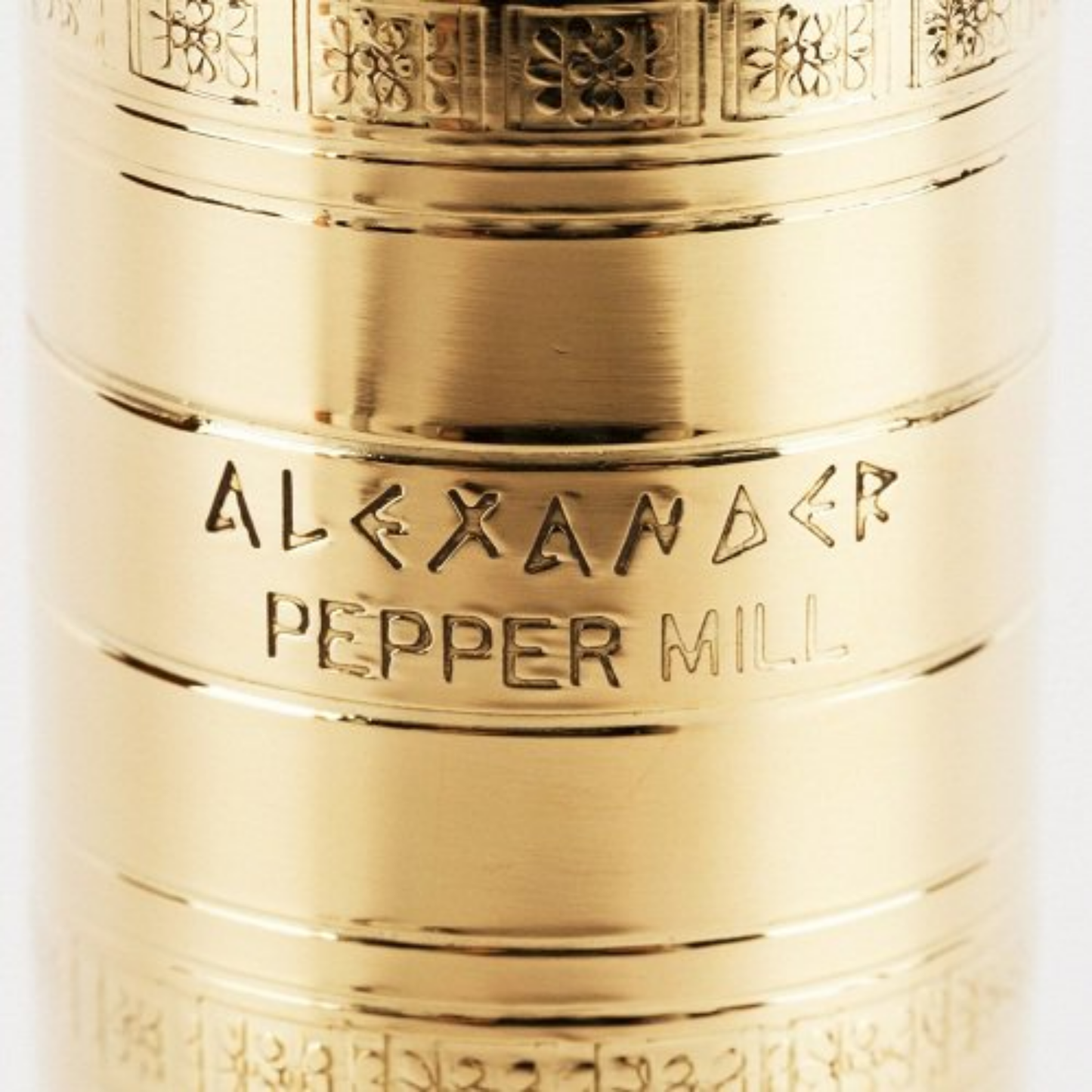 Close up view of the text from the mill that is Alexander Pepper Mill from Alexander Mills Brass Pepper Mill #104 - Brass, 230mm / 9" tall, 3DCut metal grinding system, adjustable coarse-fine, handcrafted Greek, durable polished body, easy-grind long arm, open-bottom flanged base, ideal for pepper seasoning, kitchen tool, flavor-maximizing grinder.