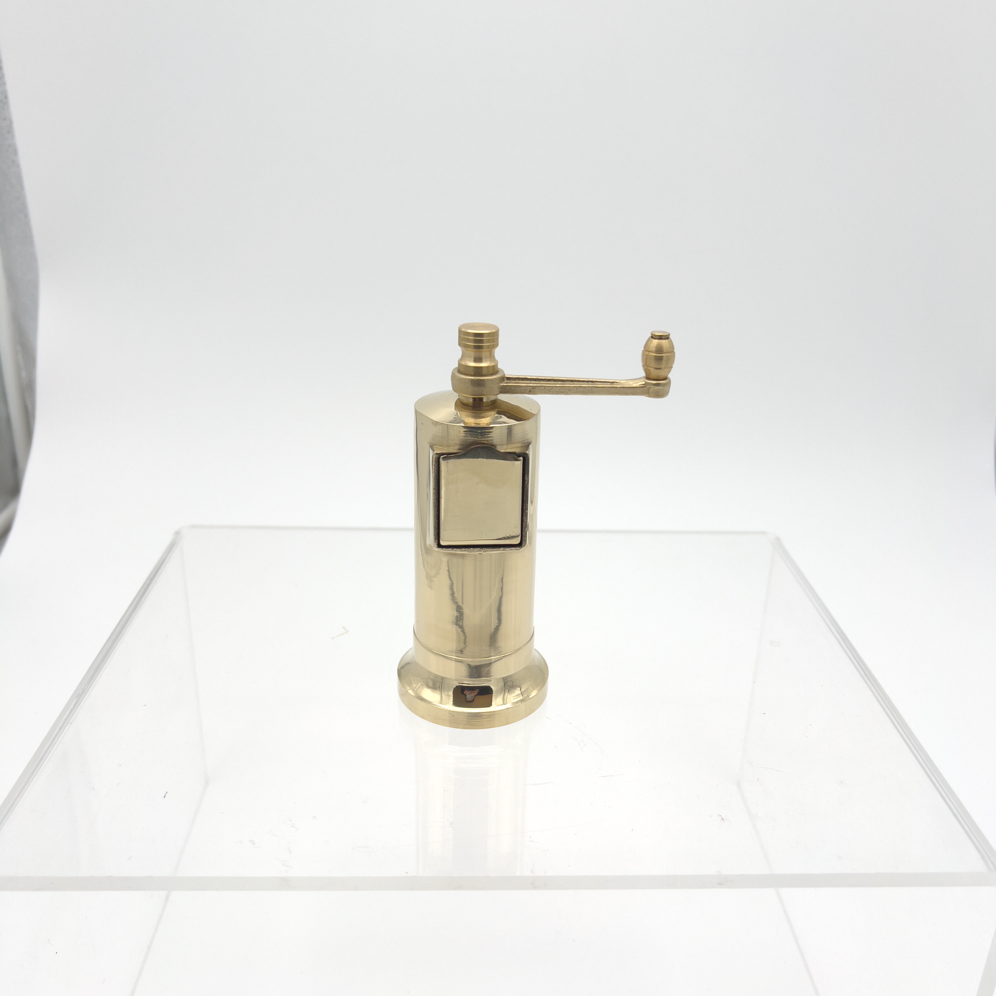 Front view on a surface Alexander Mills Cast Brass Pepper Mill #006 - Cast brass, 135mm / 5.3" tall, 3DCut metal grinding system, adjustable coarse-fine, side refill socket, handcrafted Greek, durable polished body, easy-grind long arm, open-bottom flanged base, kitchen tool, flavor-maximizing pepper grinder.