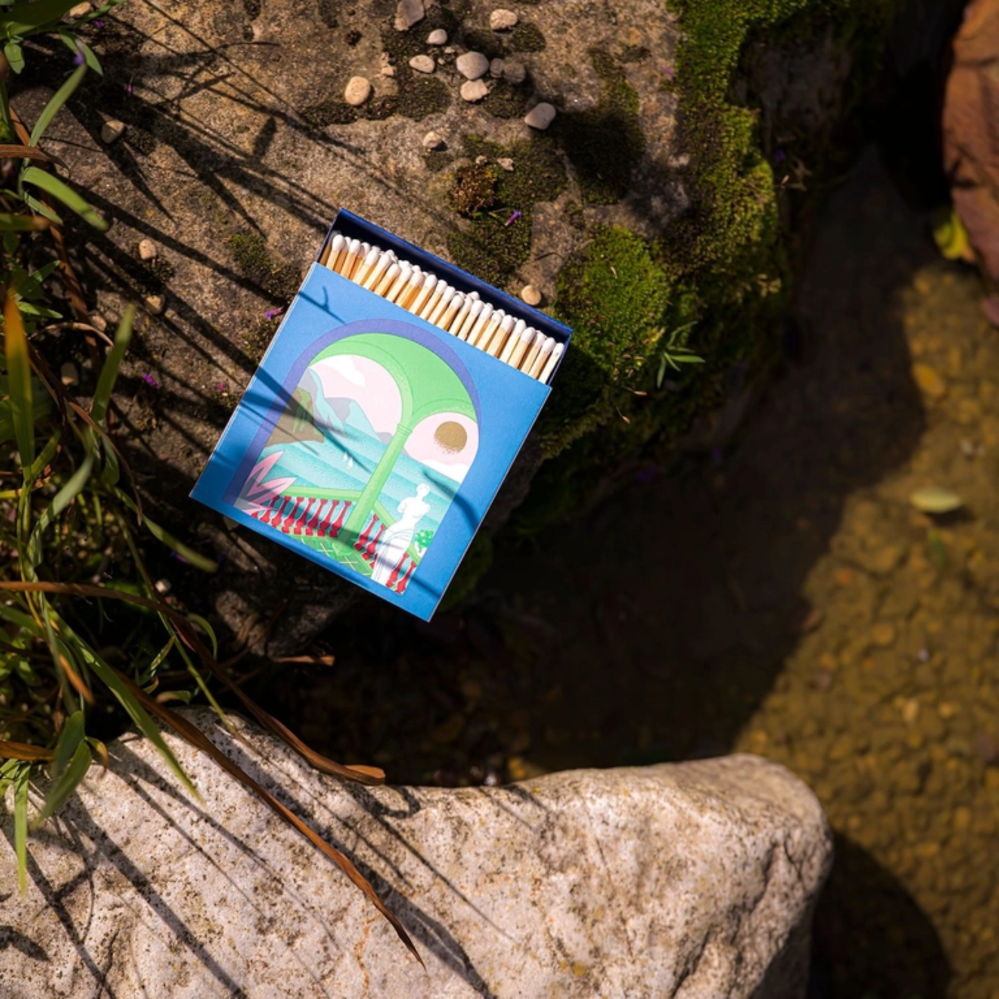 On the ground view of Archivist A Romantic View Matches - Square Green Balcony Design Matchbox with Gold Foil Sunset - 125 Natural White-Tipped Matches in Blue Tray - FSC Wood, UK Made, Eco-Friendly Gift Decor