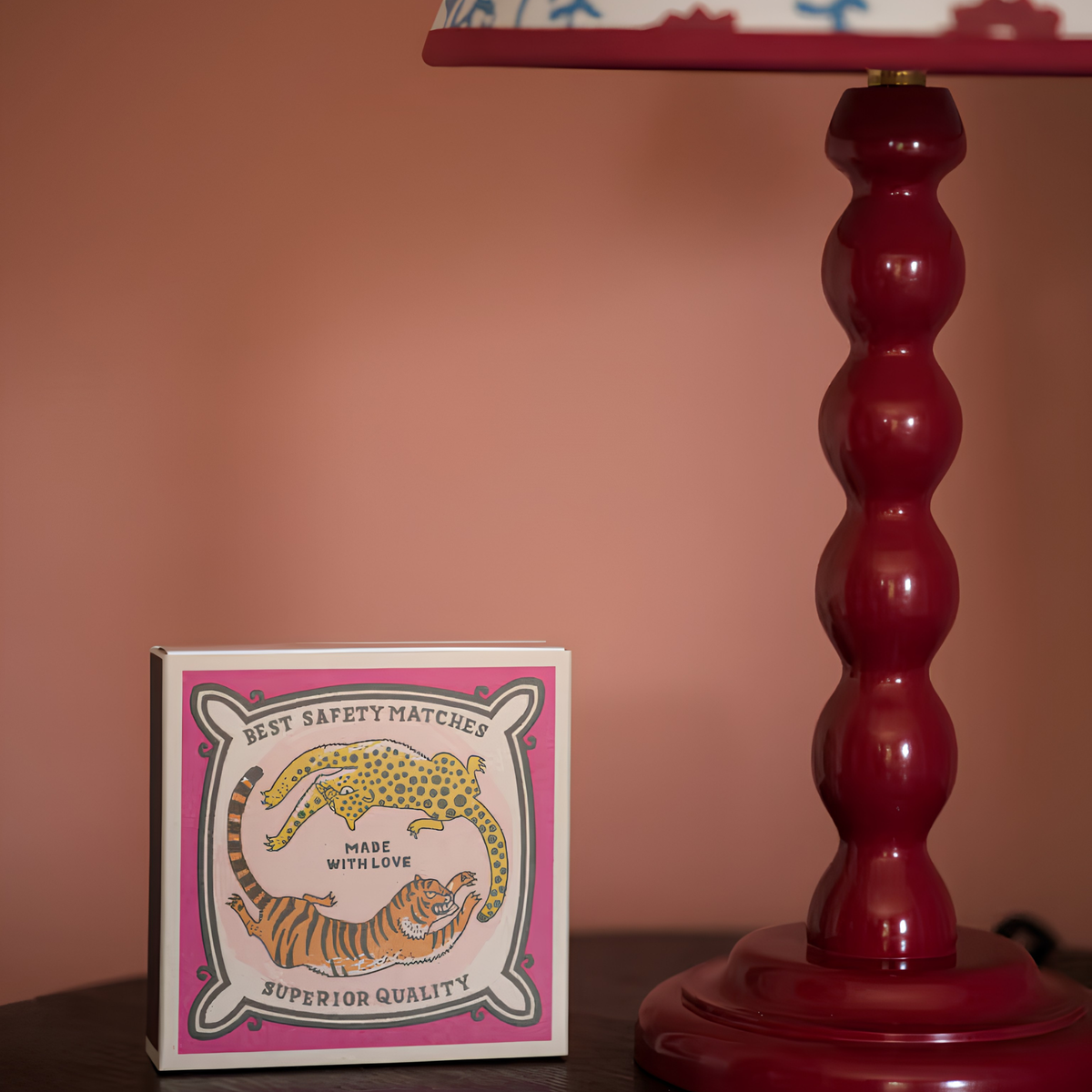 Archivist Luxury Matches Chasing Big Cats in multicolour, FSC Mix certified paper matchbox with cheetah and tiger illustrations, containing 125 natural wooden matches with white tips, shown beside a table lamp.