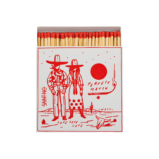 Front view and open Archivist Luxury Matches Cowboy Perfect Match: Features a Western scene of a cowboy and cowgirl beneath the sun with the words "Perfect Match, Love love, love." Contains 125 matches (100 mm, red tips), letterpress printed in the UK with FSC-certified wood and wrapped in compostable cello-perfect for coffee tables, mantelpieces, or gifting.