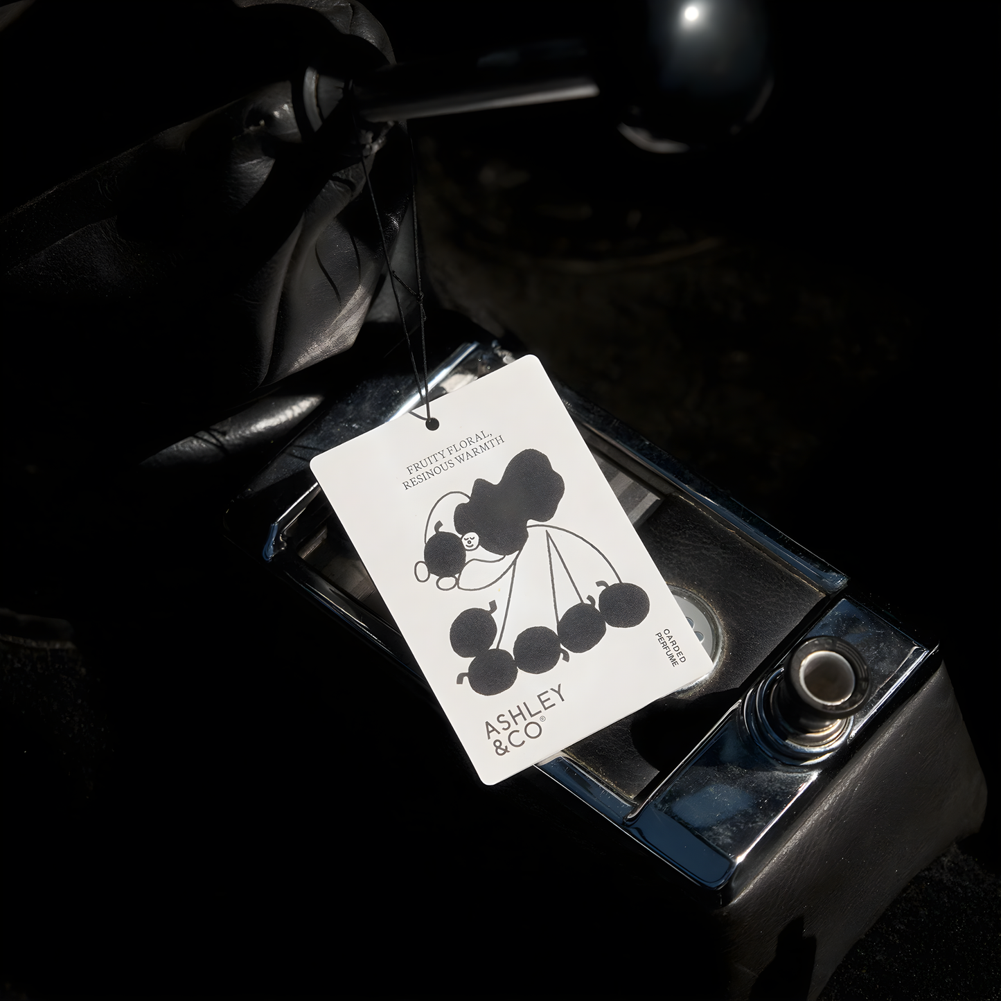 Front view of the Ashley & Co Carded Perfume Air Freshener Bonberry hung on the car gear knob.