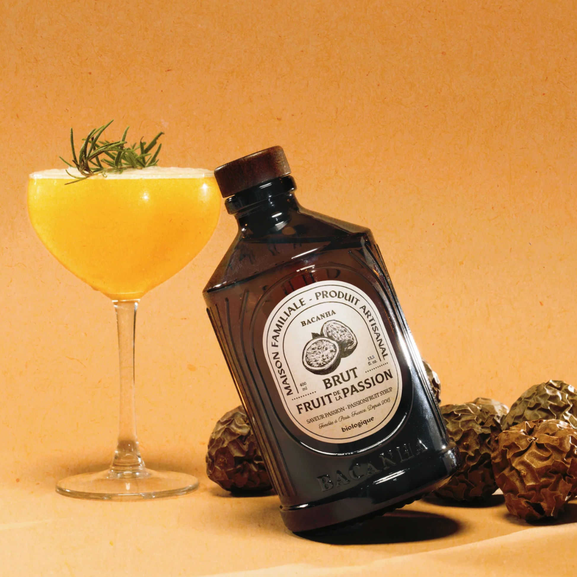 Bacahna sirop on display with passion fruit cocktail and passion fruits on orange background