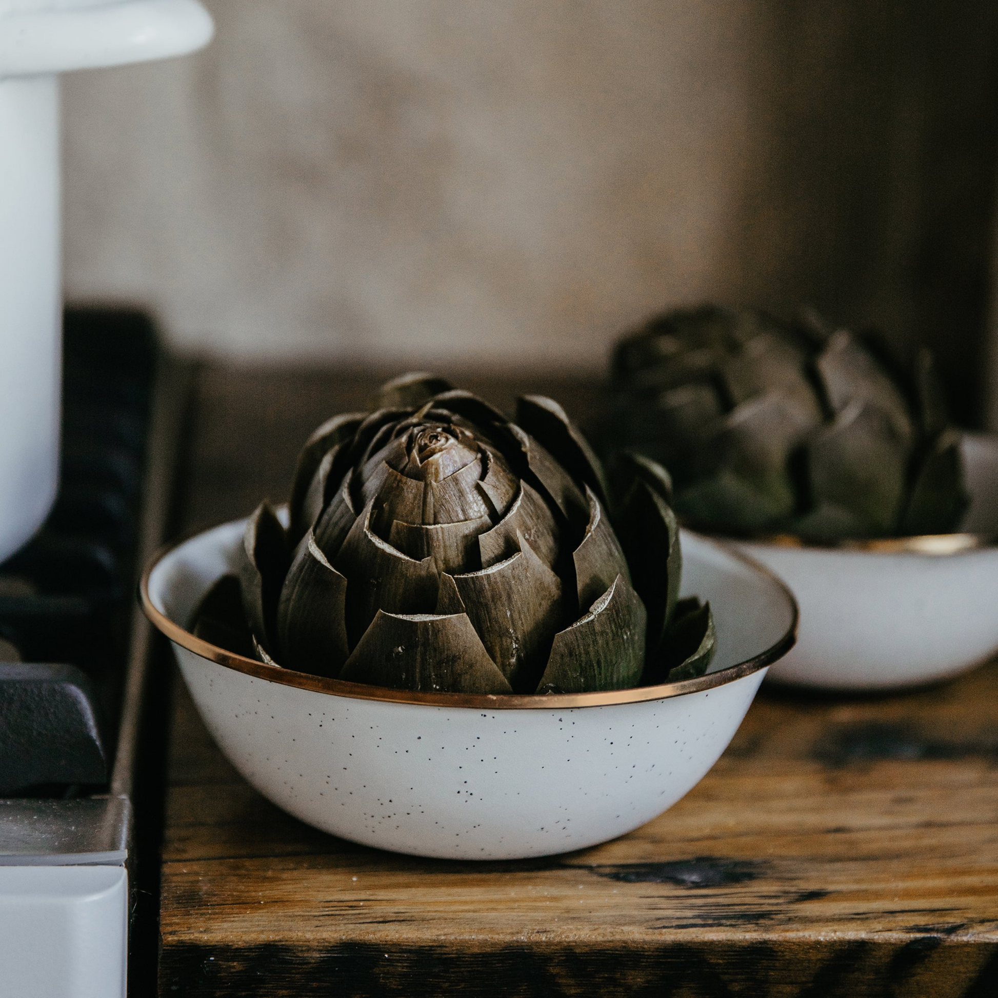 Barebones enamel bowl eggshell being used to hold artichokes while cooking