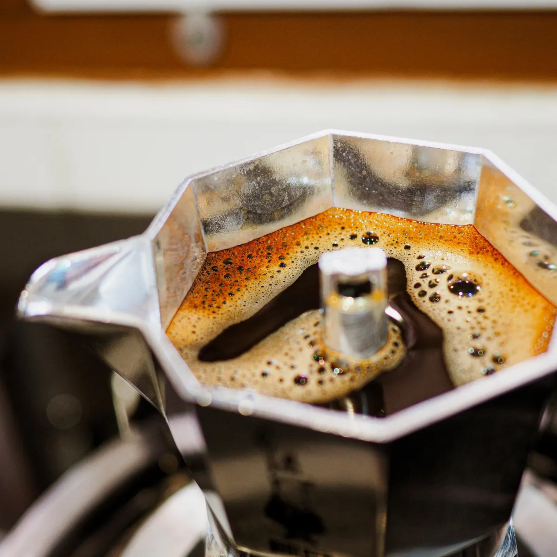 Upclose view of the coffee made in the Bialetti Moka Express 1-cup stovetop coffee maker, compact aluminum model with black handle and knob, designed to brew rich Italian espresso with a full-bodied aroma, Made in Italy.