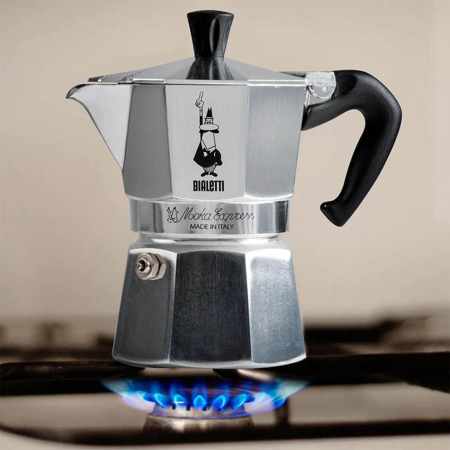 Bialetti Moka Express 1-cup stovetop coffee maker, compact aluminum model with black handle and knob, designed to brew rich Italian espresso with a full-bodied aroma, Made in Italy, shown in a stove.