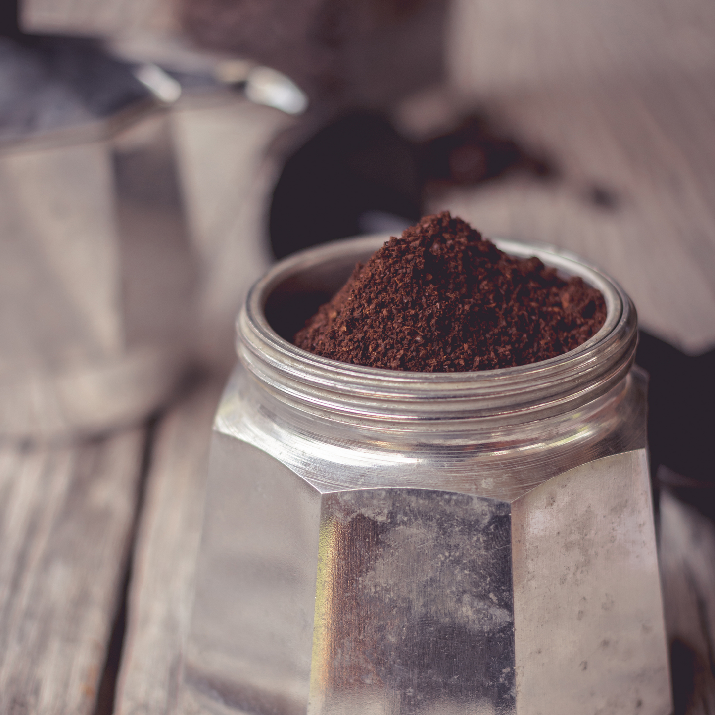 Lower chamber with powdered coffee of Bialetti Moka Express 2-cup stovetop coffee maker, small aluminum model with black thermoplastic handle and knob, ideal for brewing up to two cups of authentic Italian espresso with rich crema.