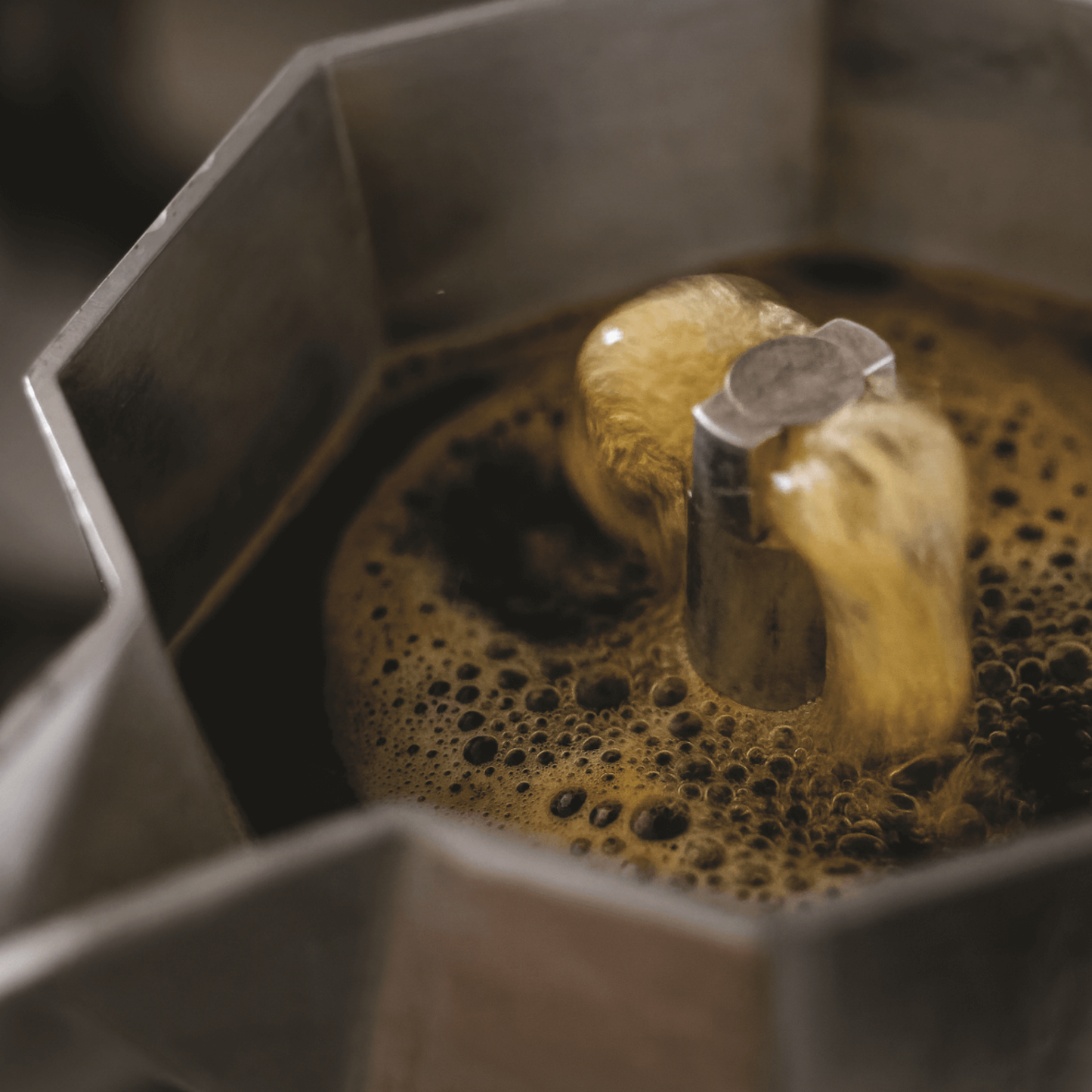 Open with boiling coffee made from Bialetti Moka Express 4-cup stovetop espresso maker, aluminum body with black handle and knob, classic octagonal design that produces smooth, aromatic espresso for four servings.