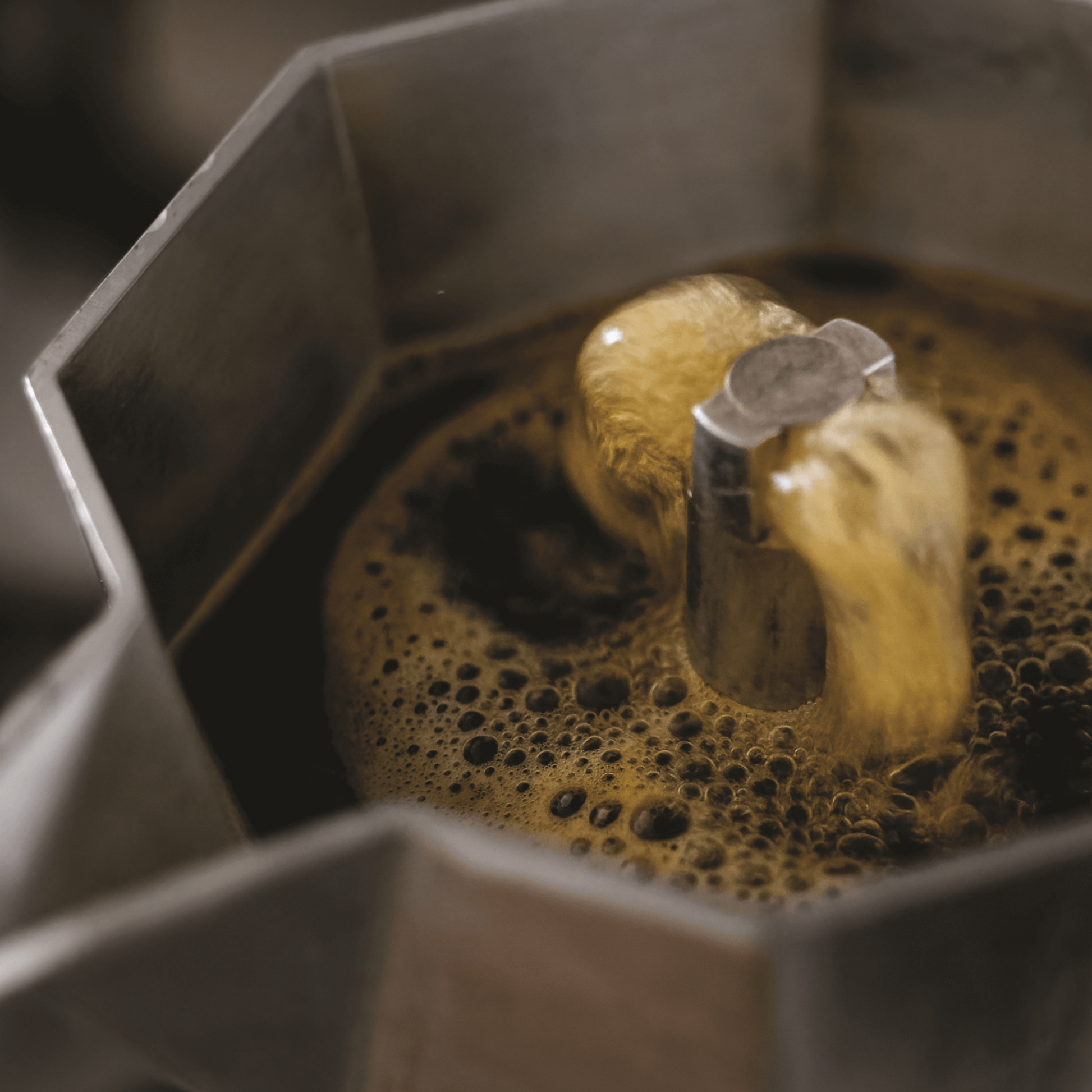 Open with boiling coffee made from Bialetti Moka Express 4-cup stovetop espresso maker, aluminum body with black handle and knob, classic octagonal design that produces smooth, aromatic espresso for four servings.