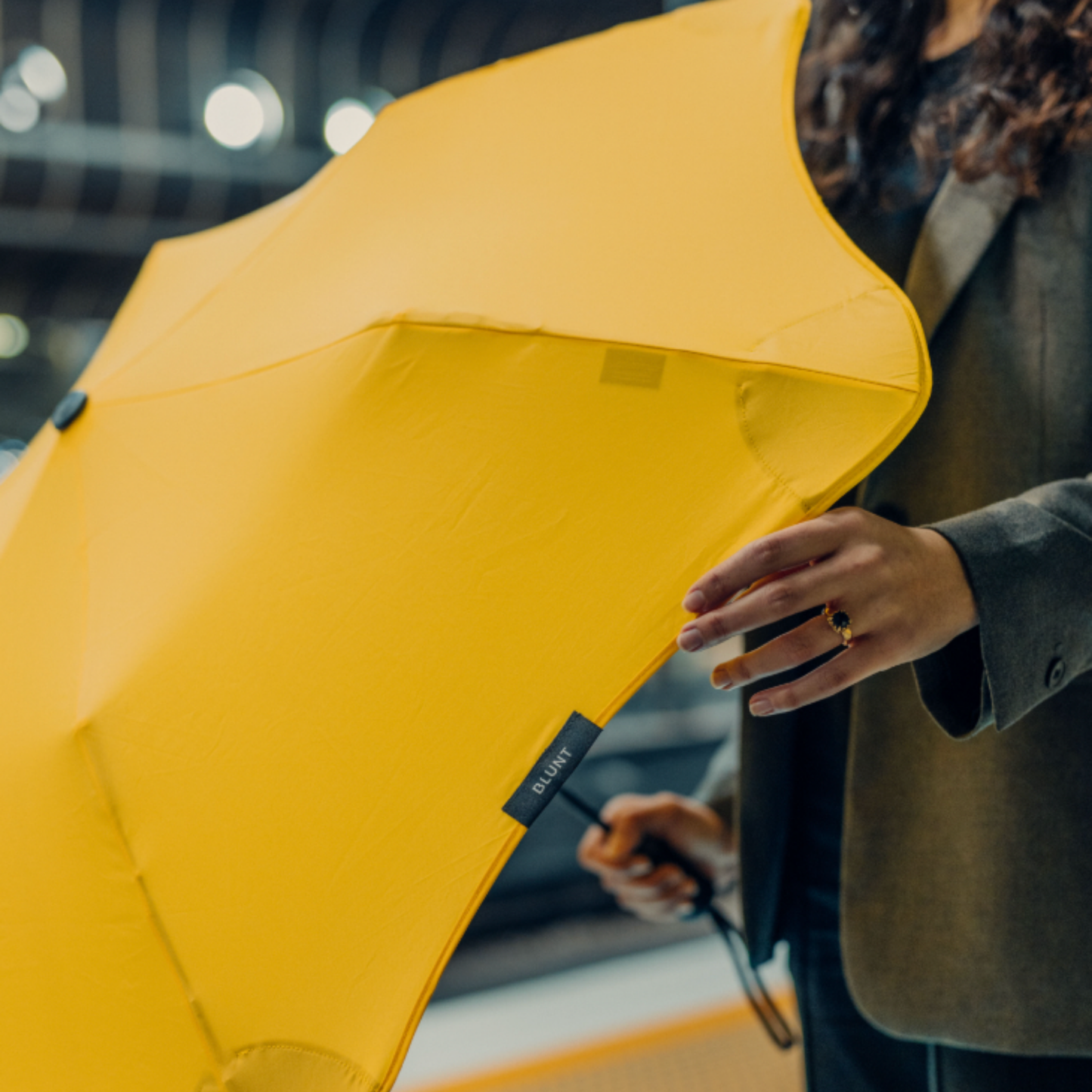 Close up of Blunt metro citrus yellow umbrella being held at hip height by woman 