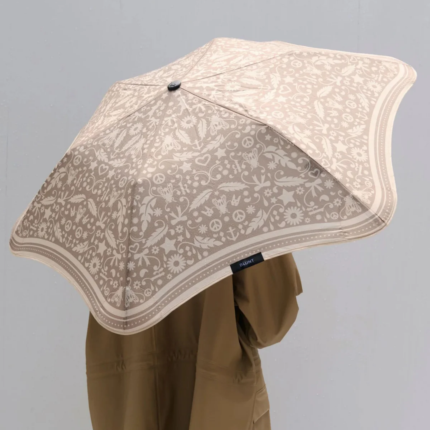 Woman holding Blunt metro Karen Walker umbrella over her shoulder with her back to the camera 
