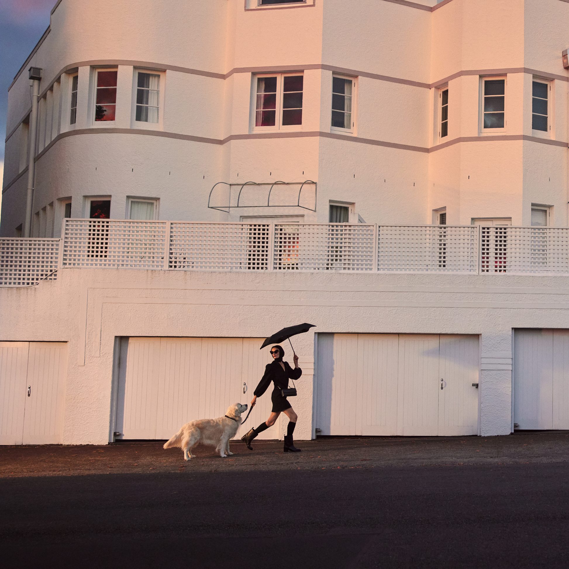 A woman walking with a dog and the Blunt Umbrella Black at 98cm, featuring a compact design with high tensioned canopy, wind tested construction and recycled rPET fabric for rain or shine.