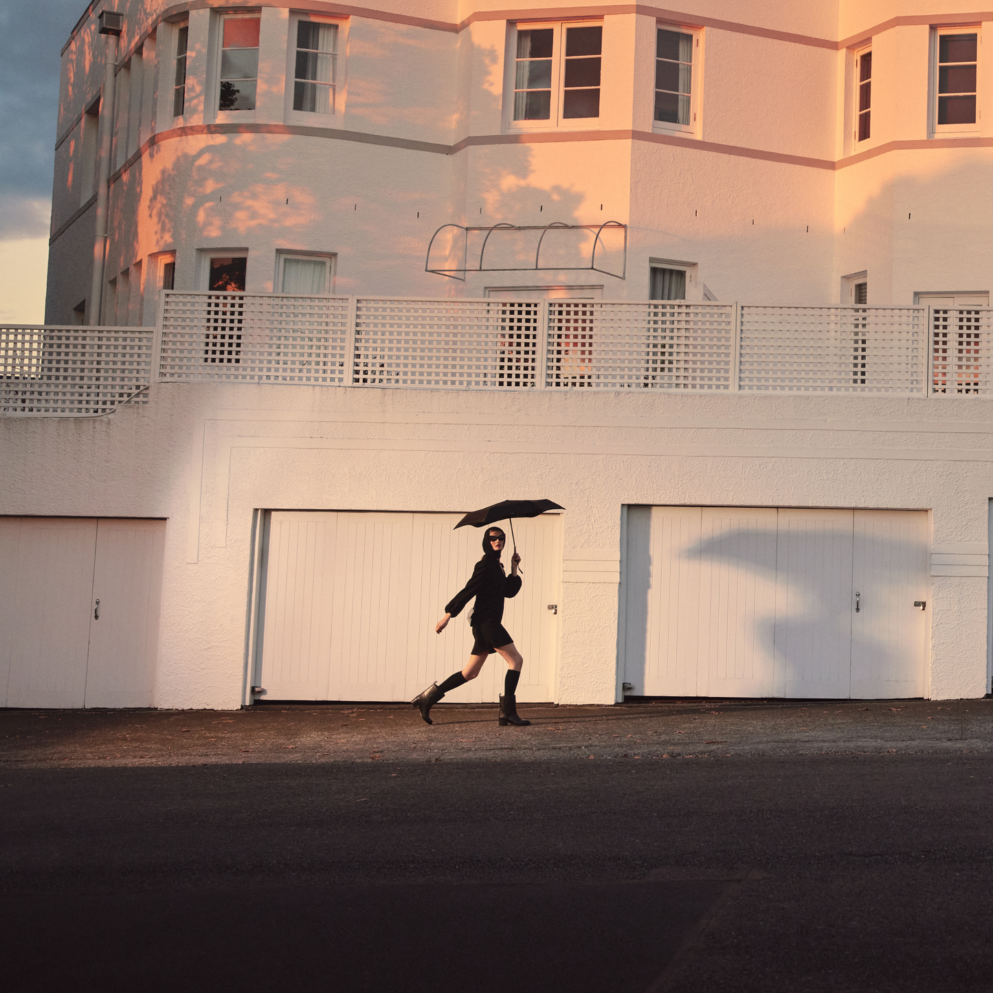Another image of a woman walking with the Blunt Umbrella Black at 98cm, featuring a compact design with high tensioned canopy, wind tested construction and recycled rPET fabric for rain or shine.