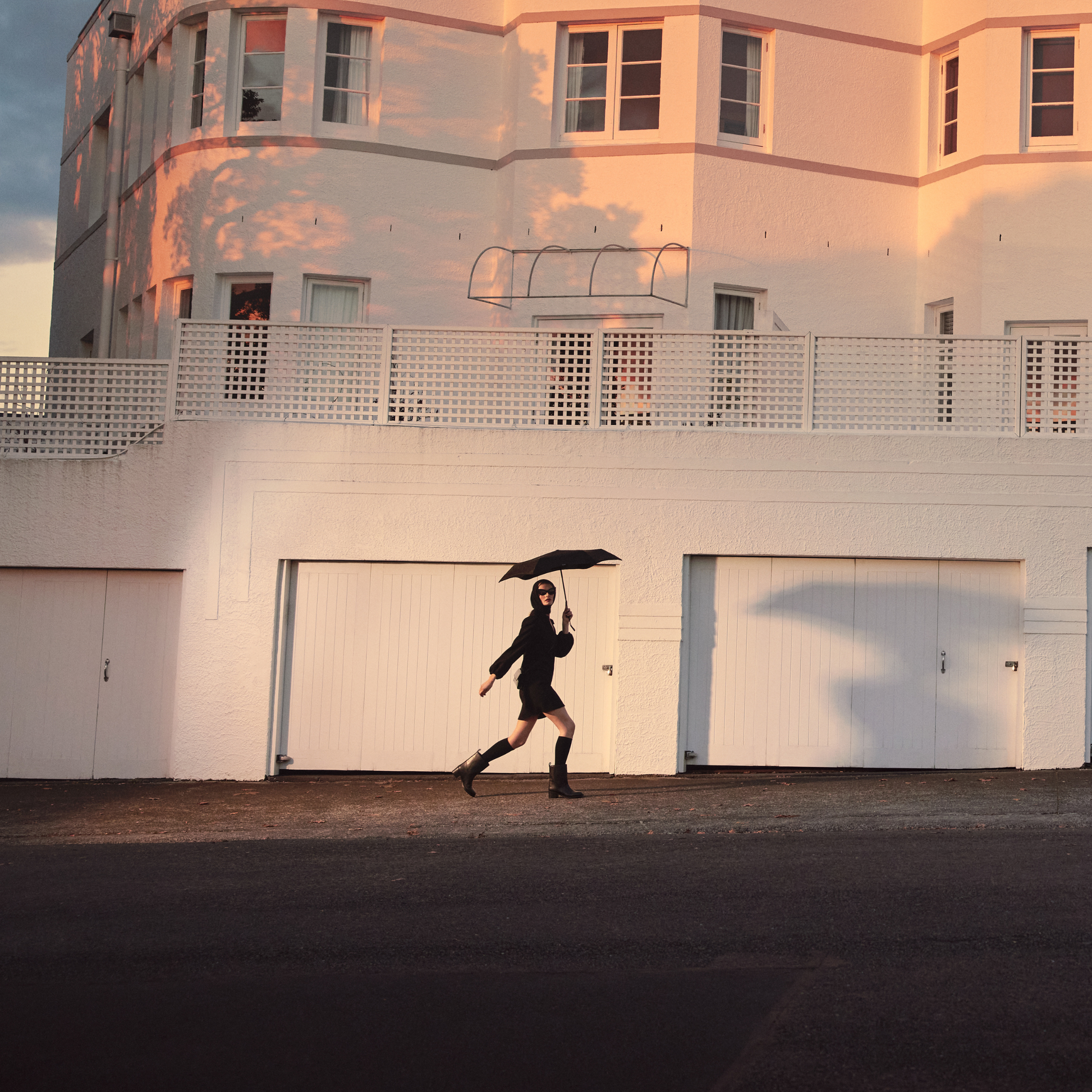 Another image of a woman walking with the Blunt Umbrella Black at 98cm, featuring a compact design with high tensioned canopy, wind tested construction and recycled rPET fabric for rain or shine.