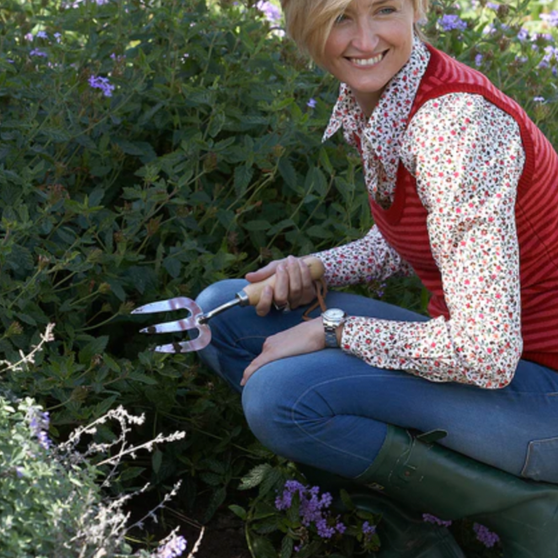 Woman using Burgon & Ball stainless steel hand fork in garden