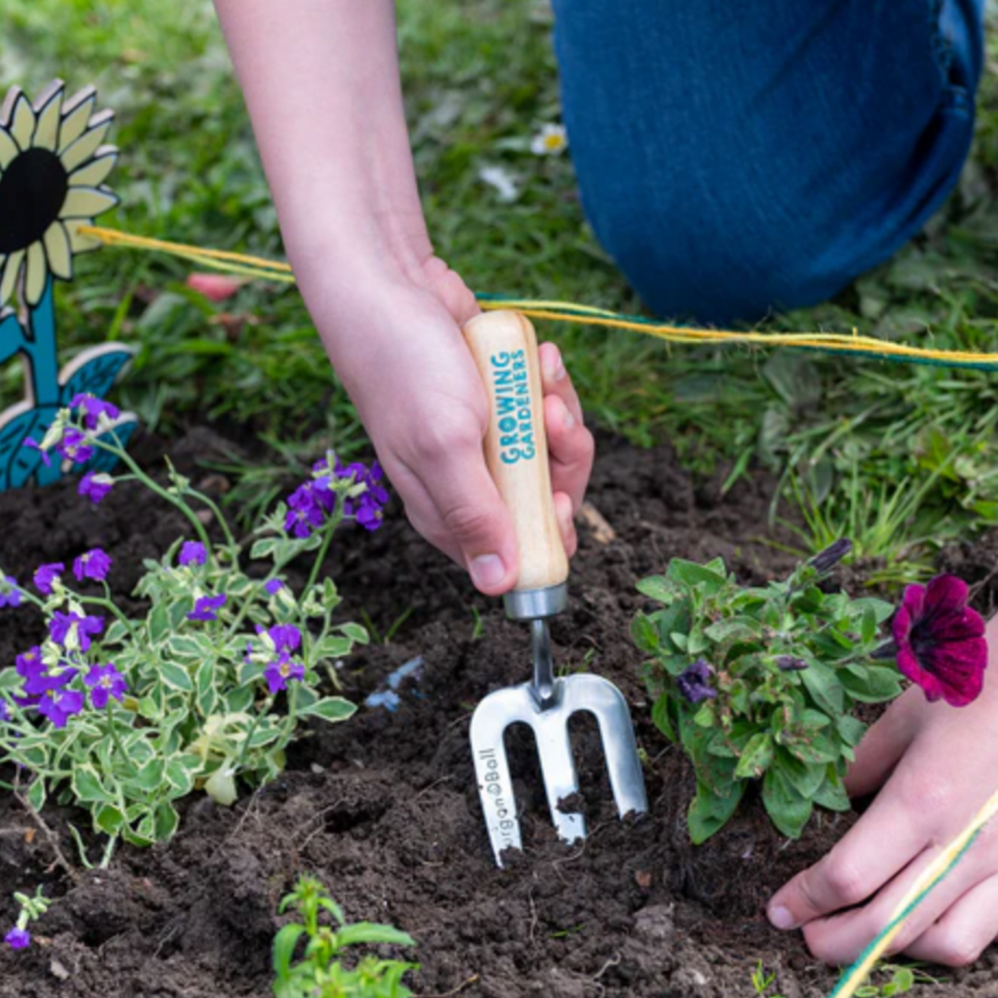 Little kid using Burgon & Ball stainless steel hand fork in garden