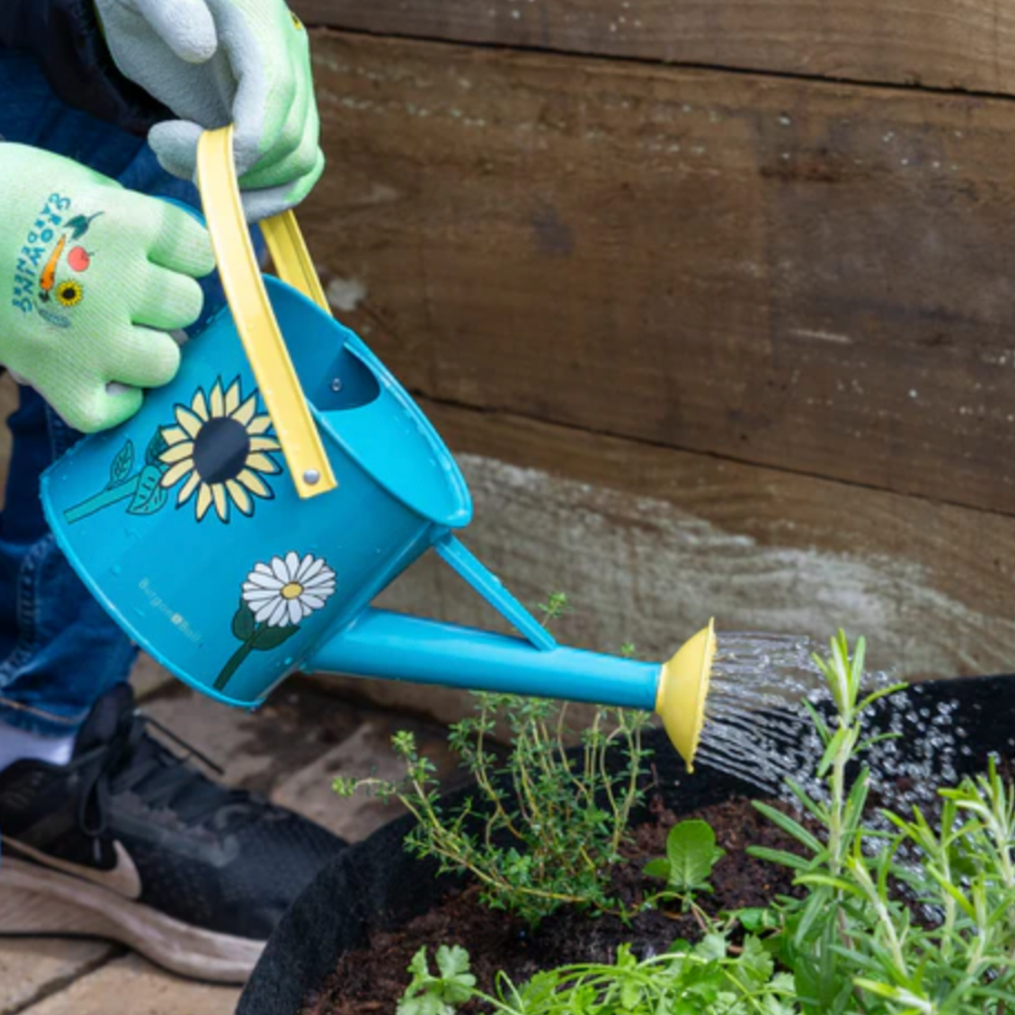 Little kid using Burgon & Ball kids watering can being used outside