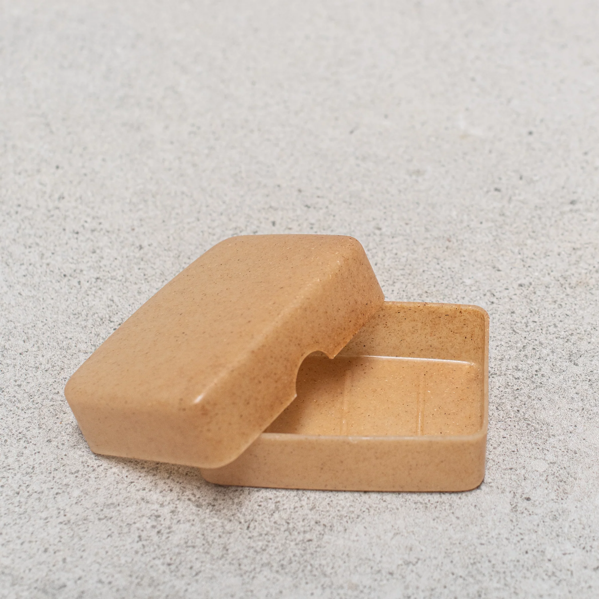 Open and empty Eco-friendly travel container by Croll & Denecke made from Arboform liquid wood, natural brown, combining natural materials like lignin and hemp for a sustainable, lightweight alternative to plastic.